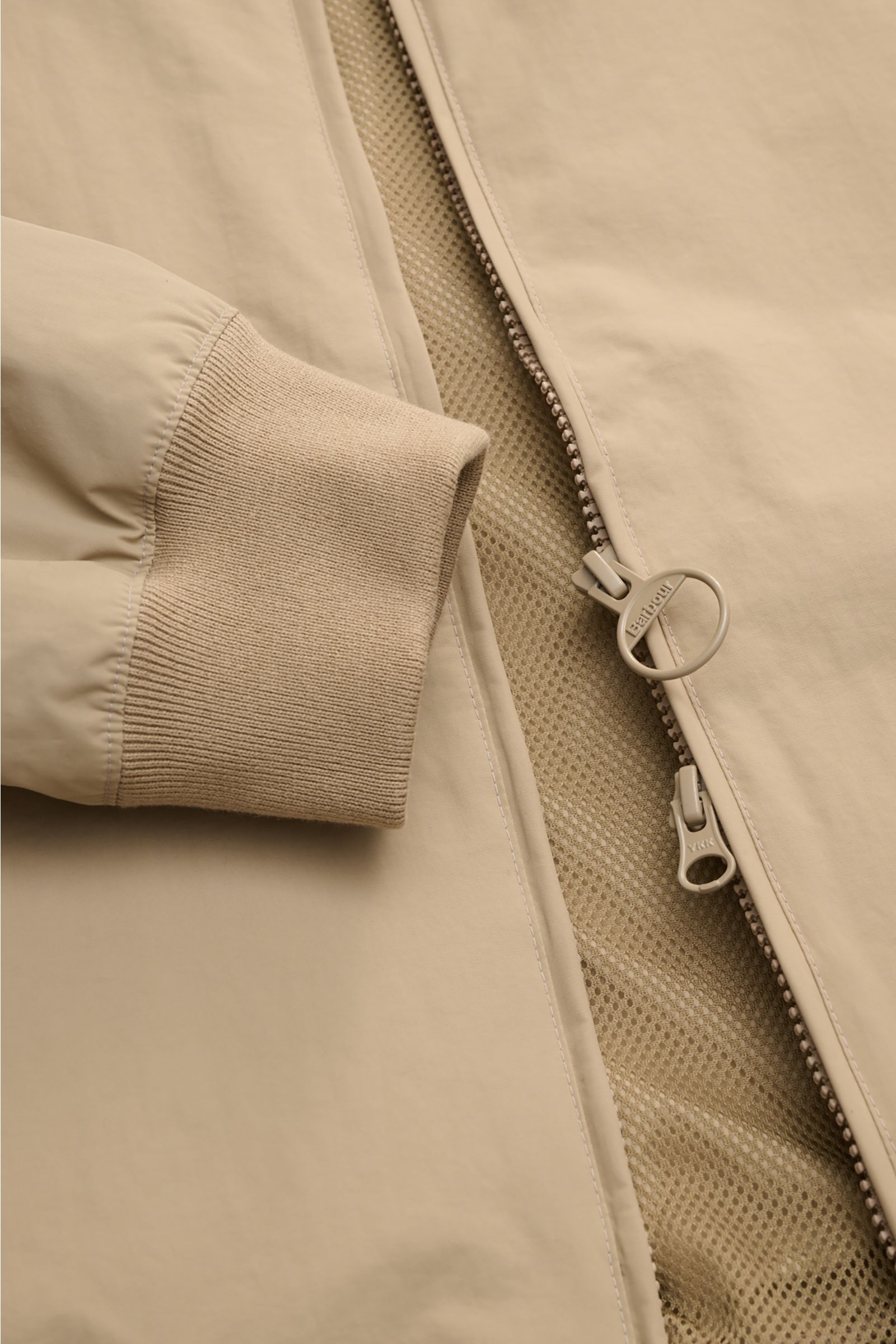 Close-up front view of Barbour Blouson 'Royston' beige jacket showing microfibre fabric, elasticated cuff, two-way zip, and mesh lining.
