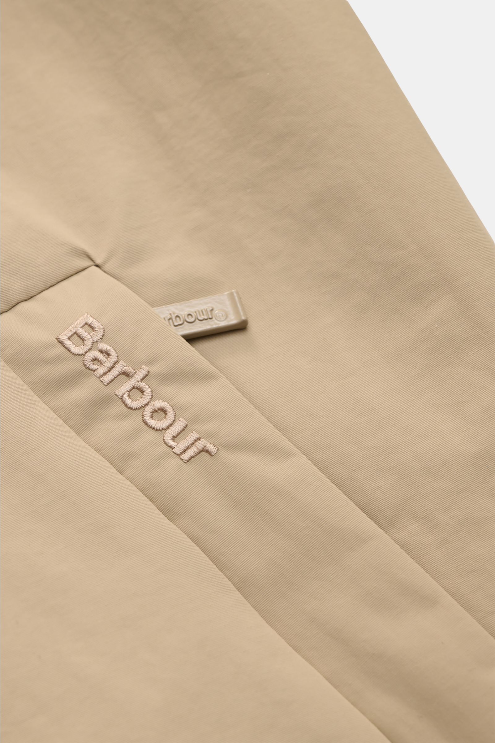 Close-up angled view of the beige Barbour Blouson 'Royston' showing embroidered logo and zipper pull on high-quality microfibre fabric.

Modern blouson by traditional label BARBOUR: With its short cut and signature corduroy trim on the collar, the mode