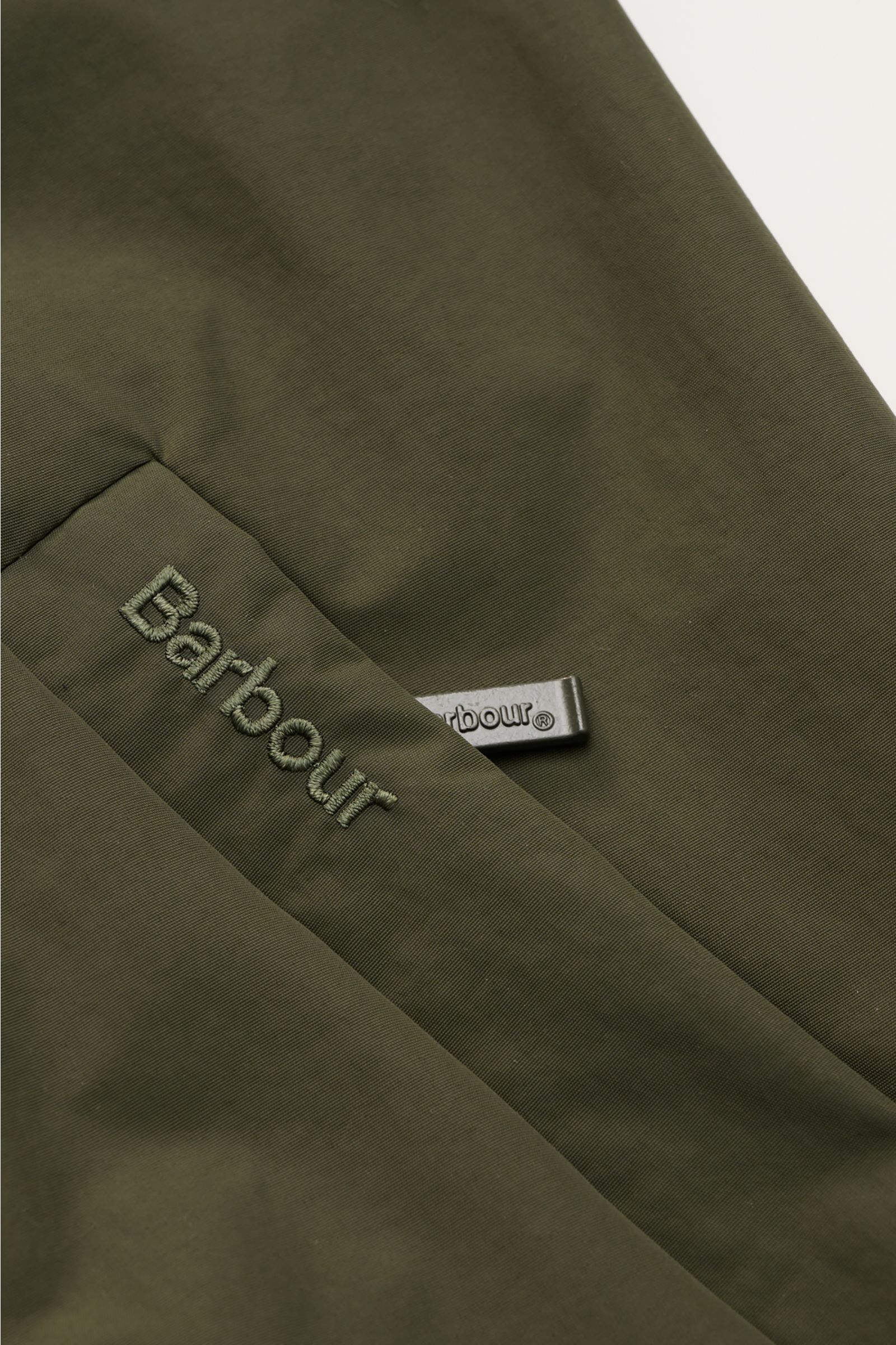 Close-up top view of the olive Barbour Blouson 'Royston' showing the embroidered logo and zipper pull on high-quality microfibre fabric. Modern blouson by traditional label BARBOUR: With its short cut and signature corduroy trim on the collar, the mode