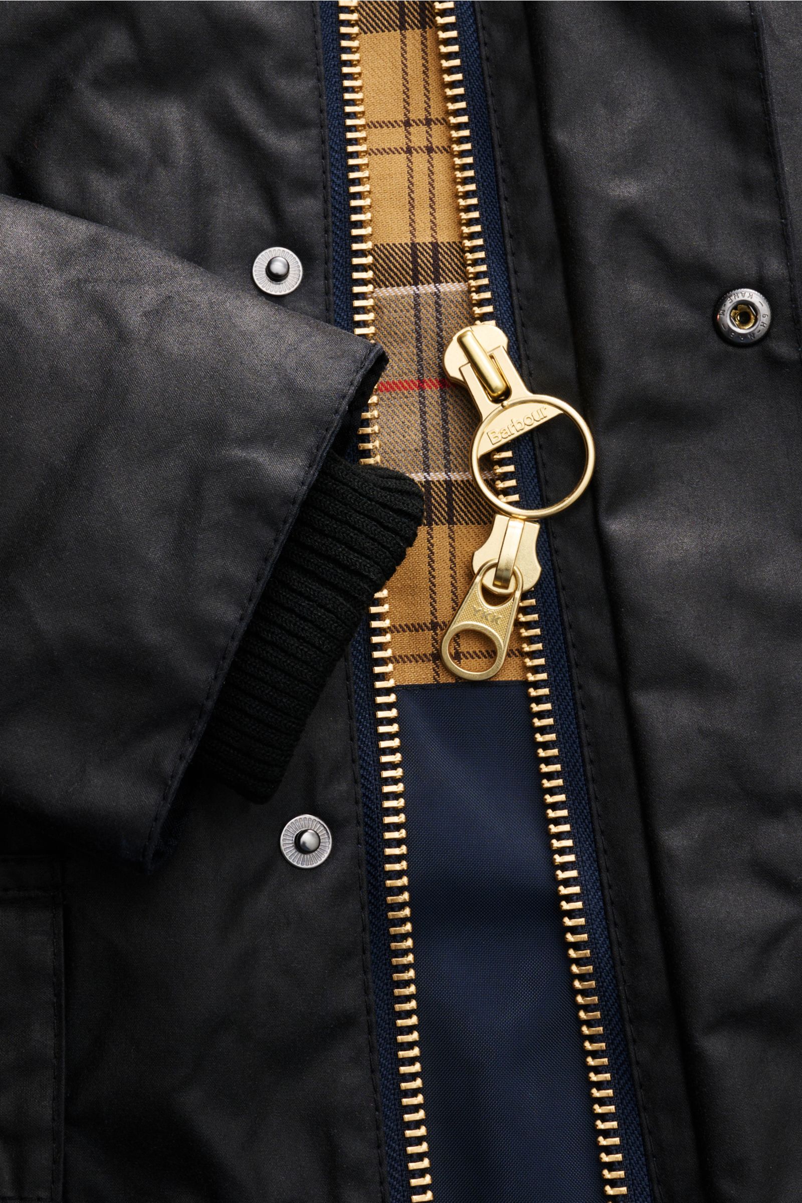 Close-up front view of Barbour Waxed jacket 'Bedale' dark navy showing waxed cotton, gold two-way zip, corduroy collar trim, snap buttons, and signature tartan lining. Perfectly equipped for the changing seasons: The 'Bedale' from BARBOUR is made from wax