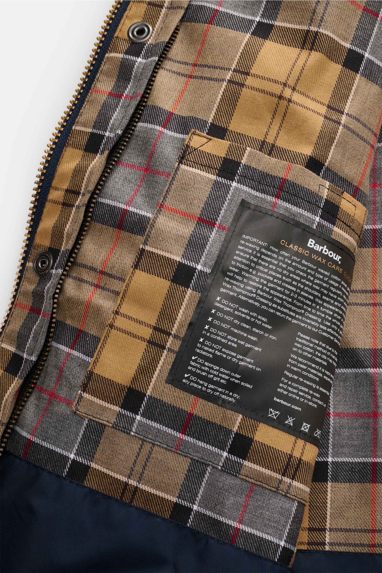 Close-up interior view of Barbour Waxed jacket 'Bedale' dark navy showing the signature tartan lining, inside pocket, and care label.

Description: Perfectly equipped for the changing seasons: The 'Bedale' from BARBOUR is made from waxed cotton and featur