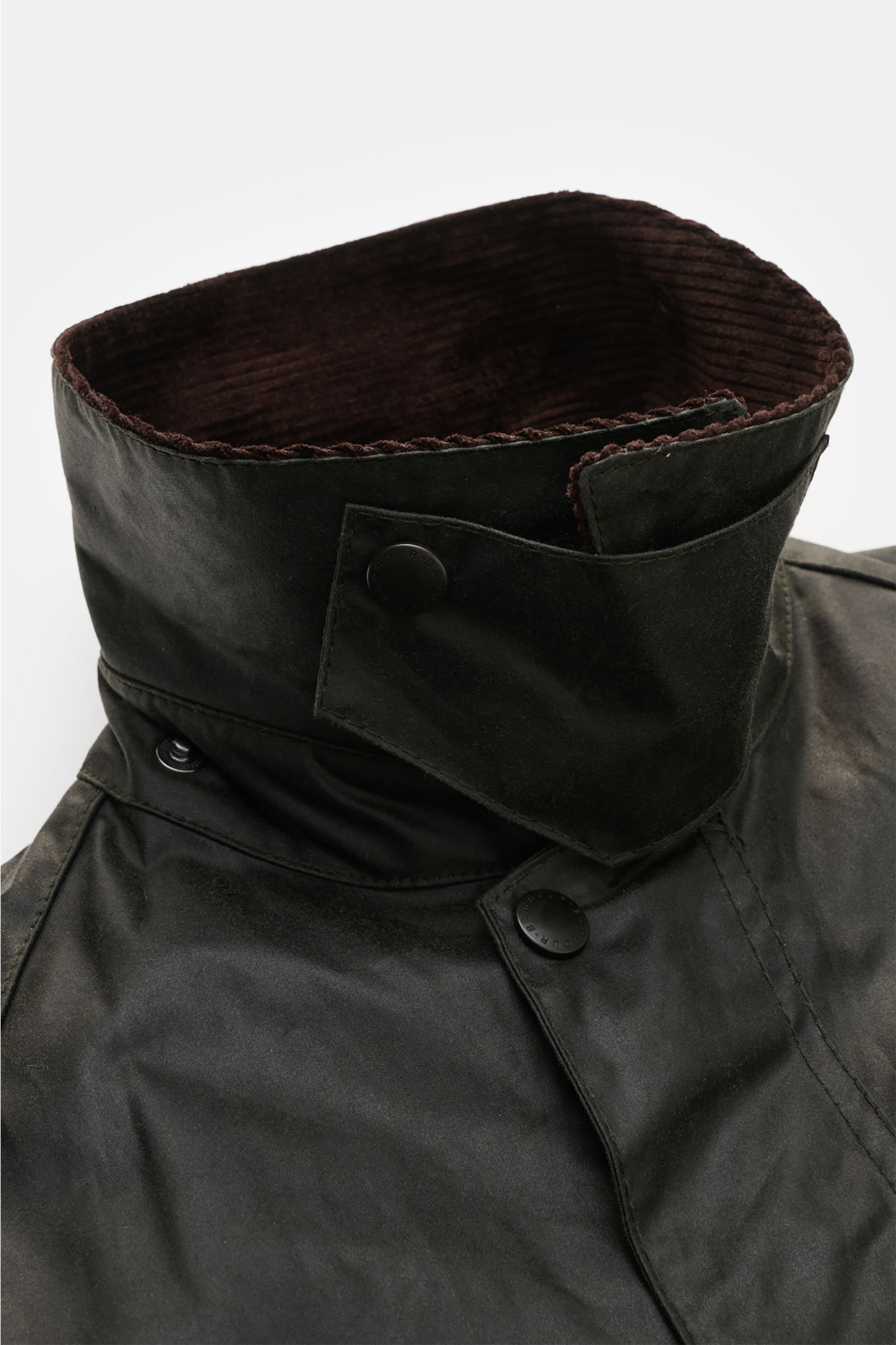 Barbour Wachsjacke 'Bedale' dunkelgrün im Detail von oben fotografiert, mit Cord-Kragen, gewachster Baumwolle und Tartan-Futter.