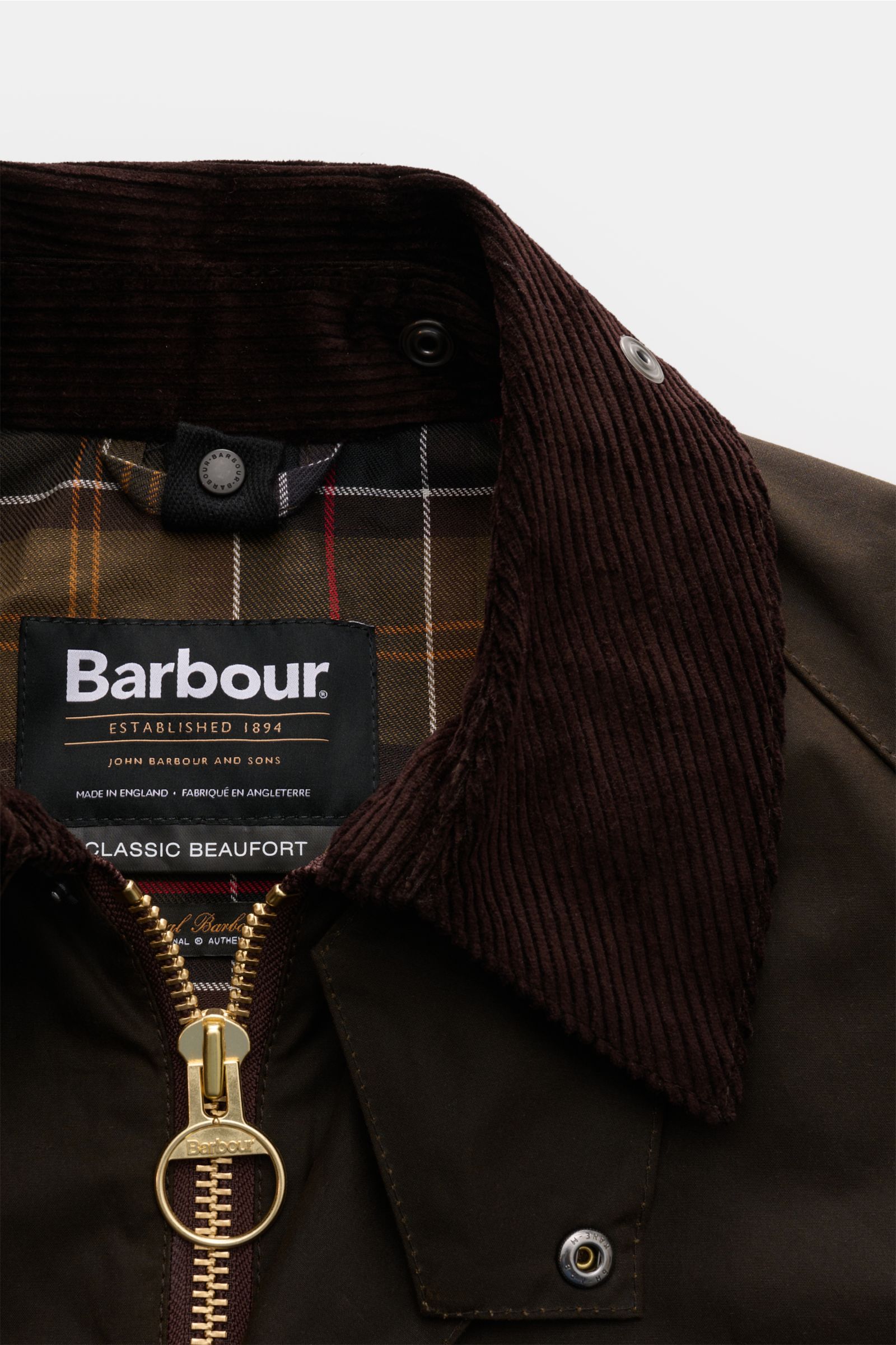 Barbour Waxed jacket 'Beaufort' dark olive shown close-up from the front, highlighting corduroy collar, gold two-way zip, and classic tartan lining. A true classic from BARBOUR: The long waxed jacket 'Beaufort' made of water repellent, waxed cotton with c