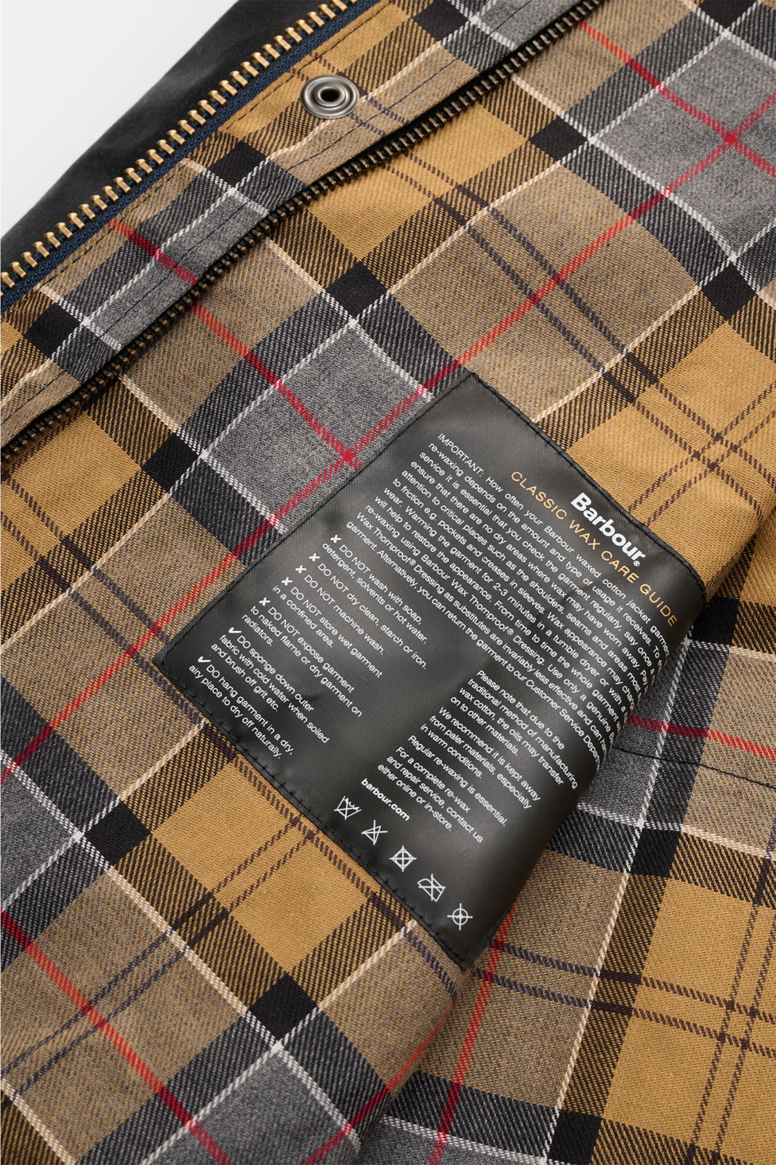 Close-up inside view of Barbour Waxed jacket 'Beaufort' dark navy showing classic tartan lining and care label with zipper edge.

Description: A true classic in the British outdoor tradition: The waxed jacket 'Beaufort' by BARBOUR is made of robust, waxed