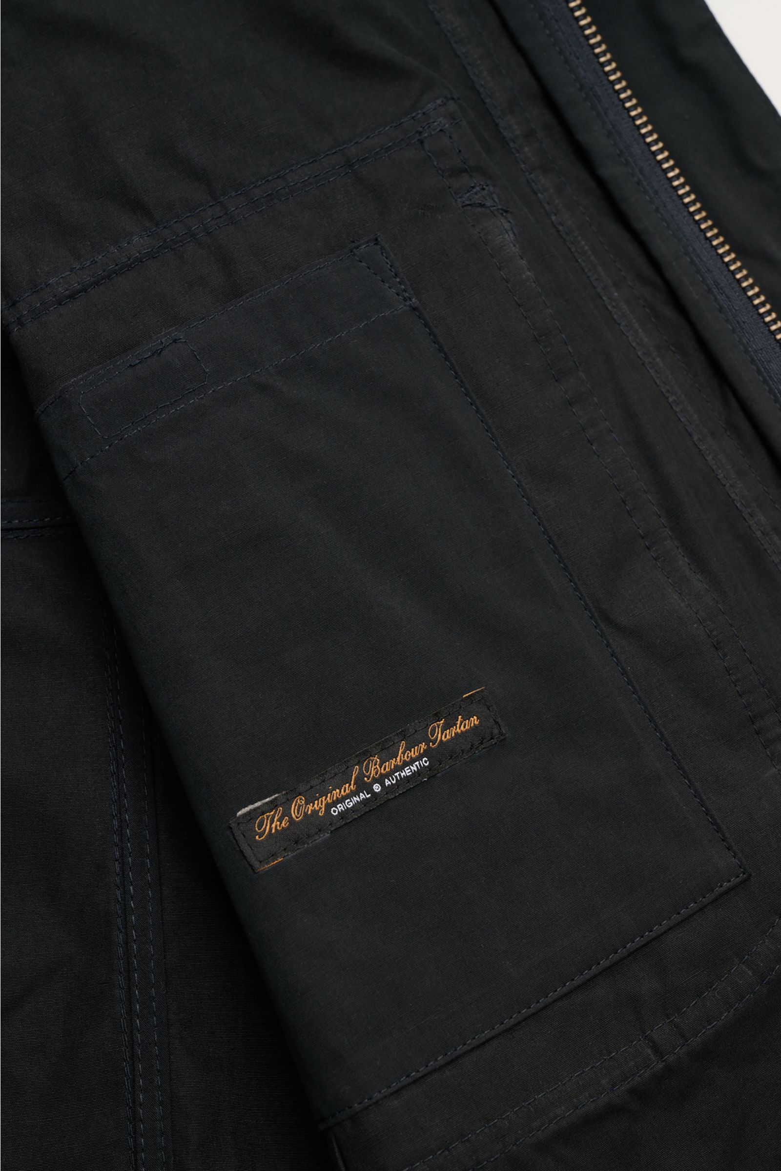Close-up view of the sleeve and inside pocket of the Barbour Field jacket 'Sanderling' navy, showing the blend cotton and microfiber fabric with a velvety feel. The image highlights the regular fit, robust two-way zip, storm flap with snap buttons, standi