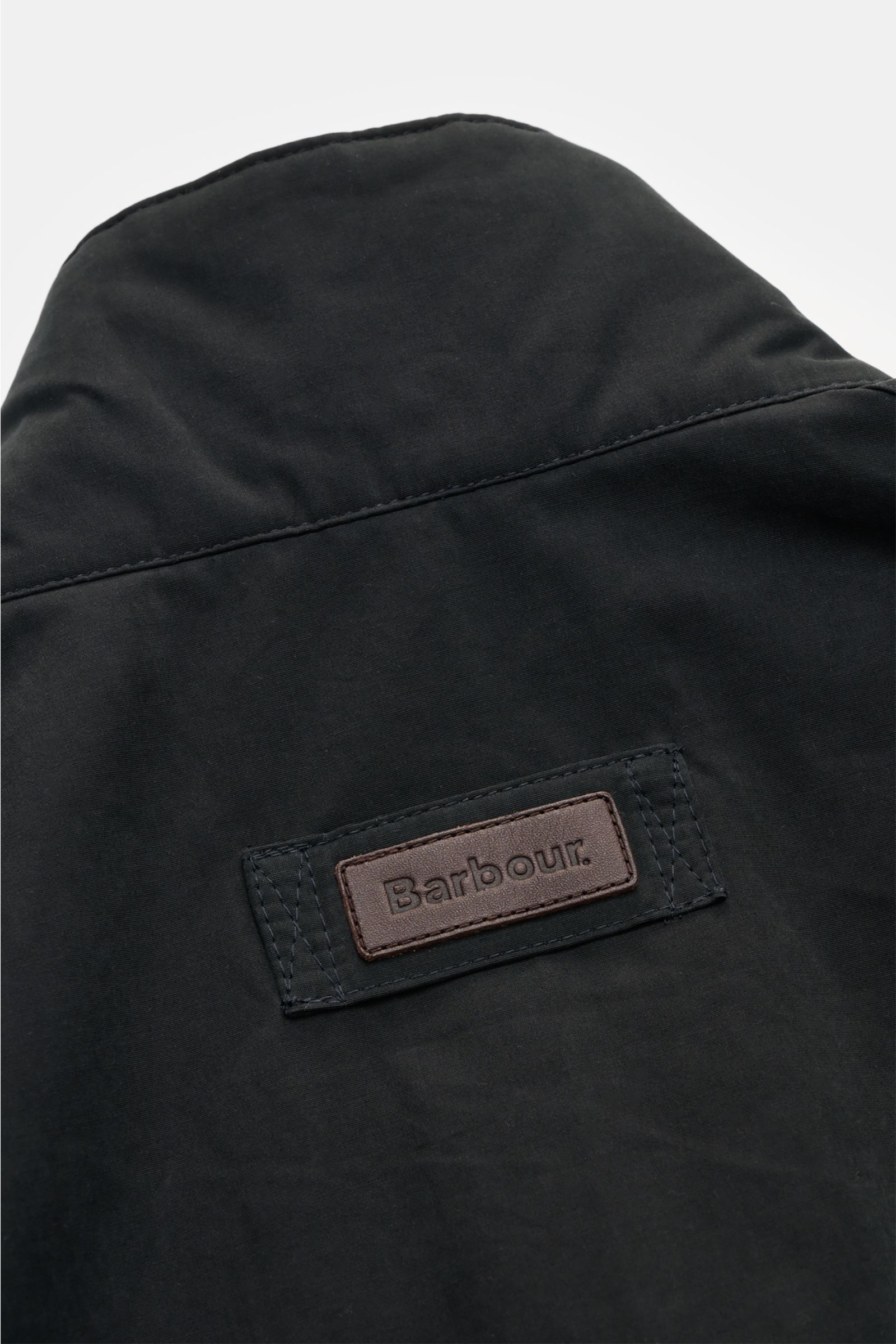 Close-up rear view of Barbour Field jacket 'Sanderling' navy showing black fabric and brown leather Barbour logo patch.

Description: Lightweight, functional and in classic style: The versatile field jacket 'Sanderling' by BARBOUR is made of comfortably l