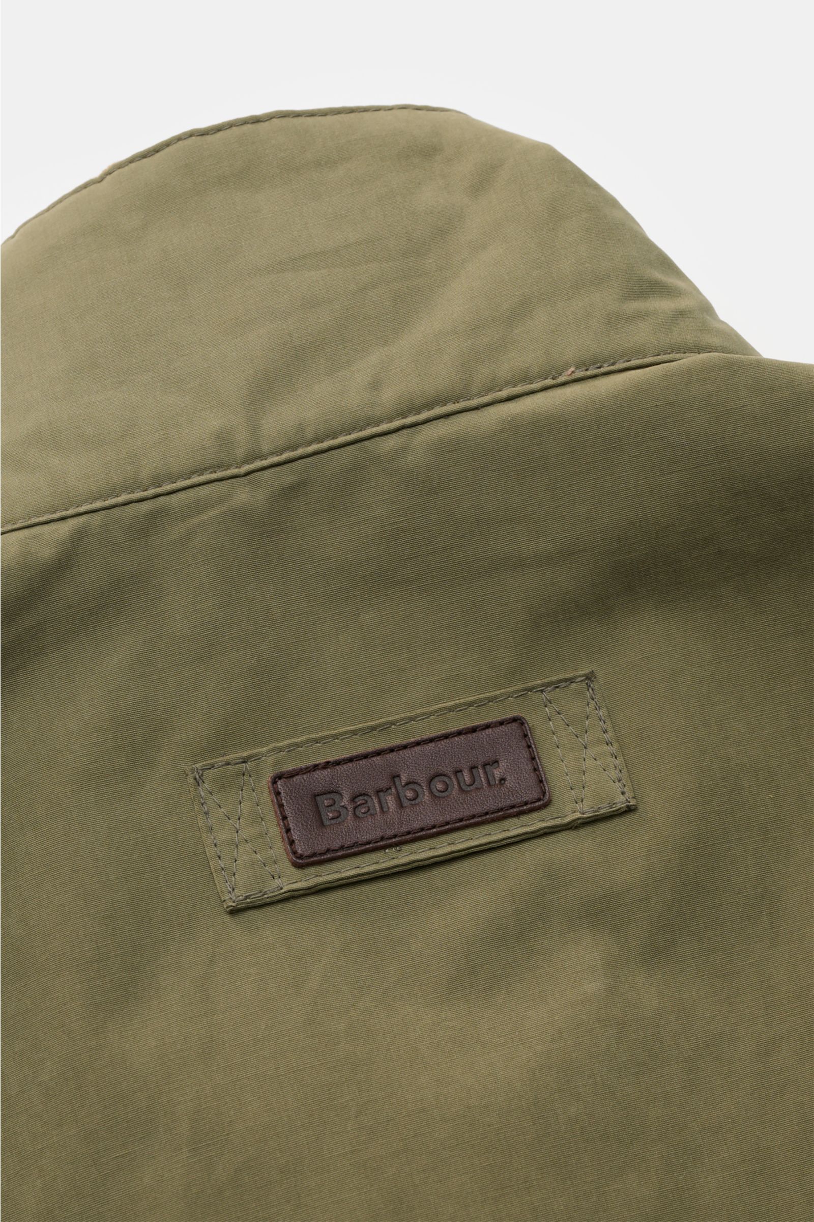 Close-up of the back collar of the Barbour Field jacket 'Sanderling' olive, showing the olive cotton-microfibre fabric and the brown leather Barbour logo patch.

Description: Lightweight, functional and in classic style: The versatile field jacket 'Sander