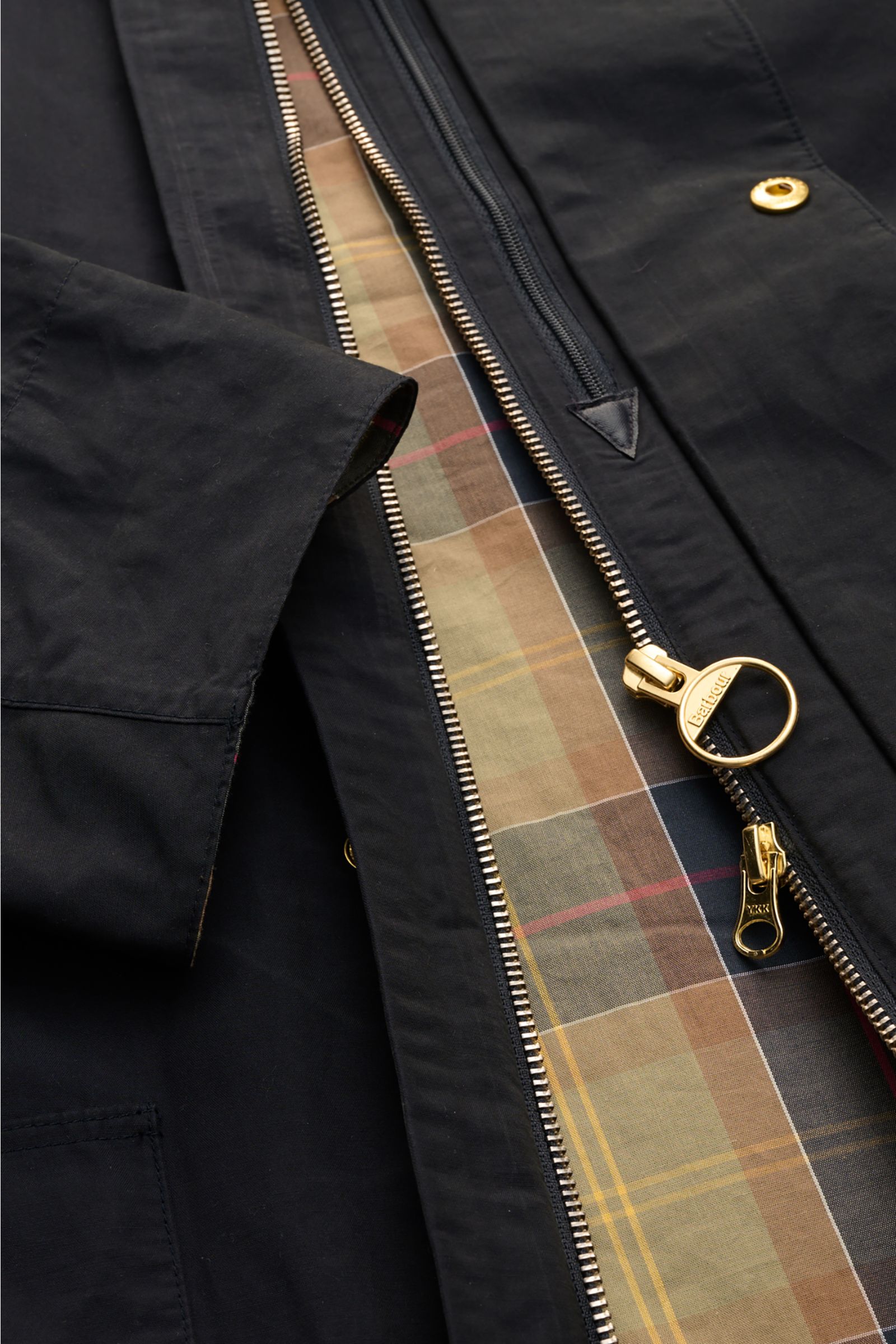 Close-up top-down view of the Barbour Parka 'Icons Border' dark navy showing gold zipper, snap button, and tartan lining.

Create classically elegant casual looks in quintessentially English style with the lightweight parka 'Icons Border' by BARBOUR – 