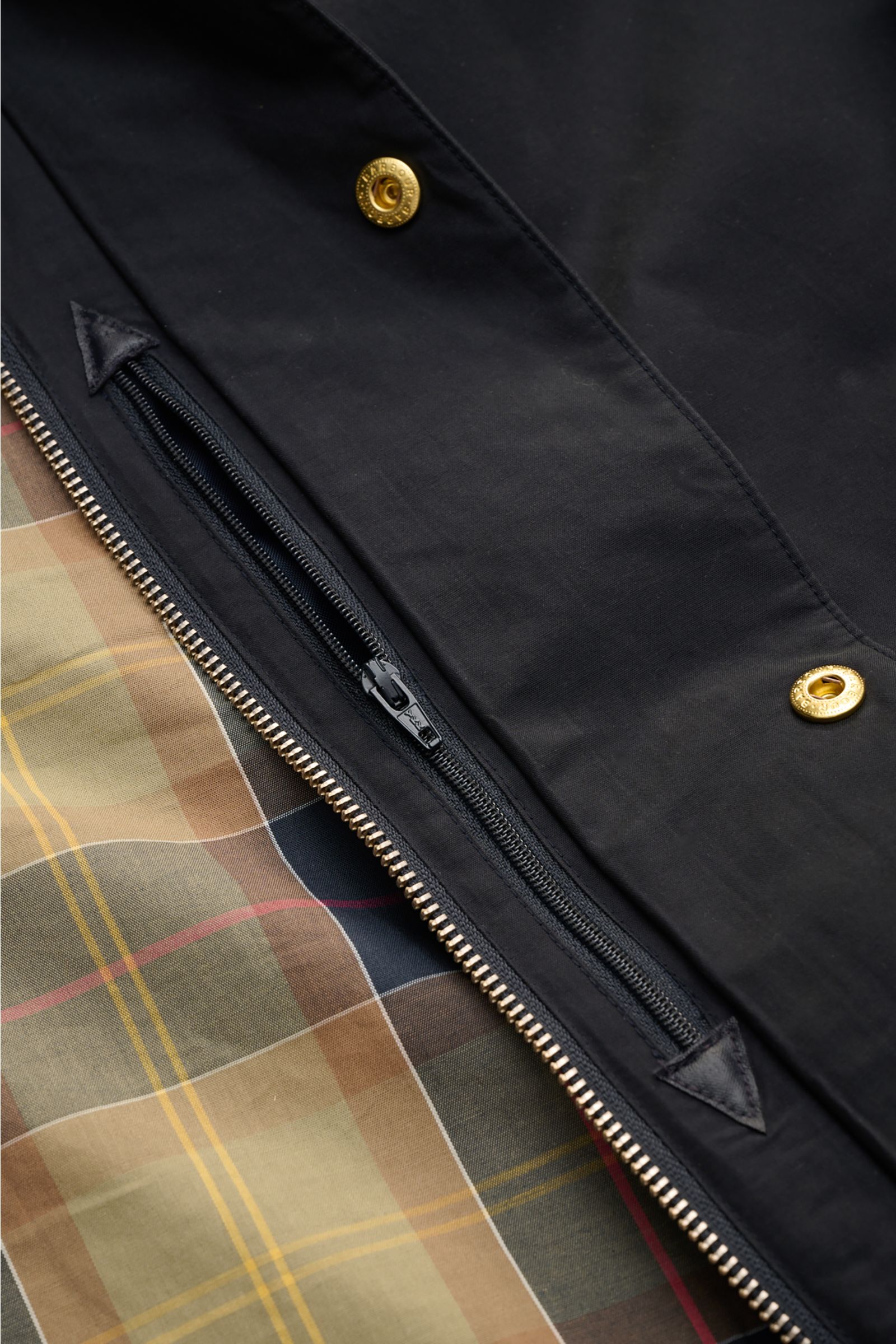 Alt tag (125 characters max):
Close-up angled view of Barbour Parka 'Icons Border' dark navy showing zipper, snap buttons, and tartan lining detail.

Detailed description:
Create classically elegant casual looks in quintessentially English style with t