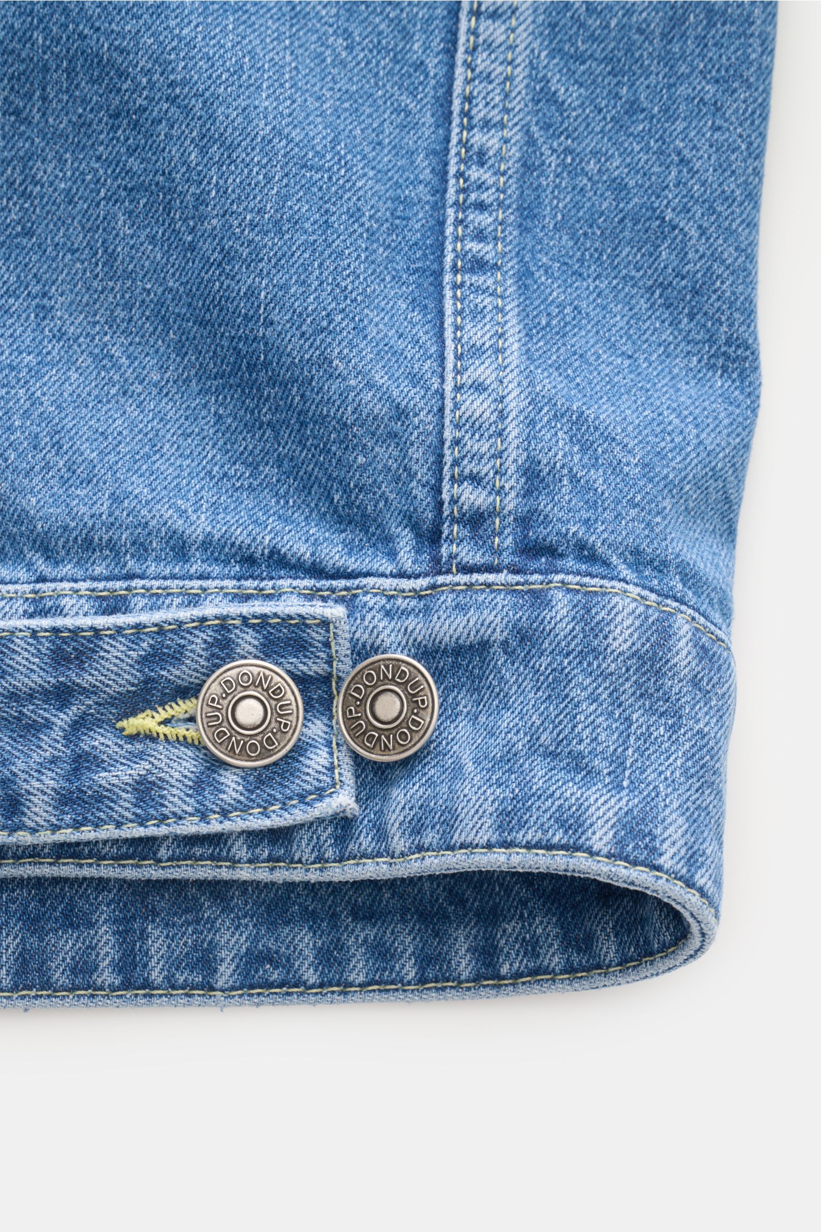 Close-up detail of the Dondup Denim jacket smoky blue hem and adjustable buttoned tab, showing contrasting seams and metal buttons.

Timeless denim essential: The DONDUP denim jacket is perfect for stylish casual looks this spring.

Denim m