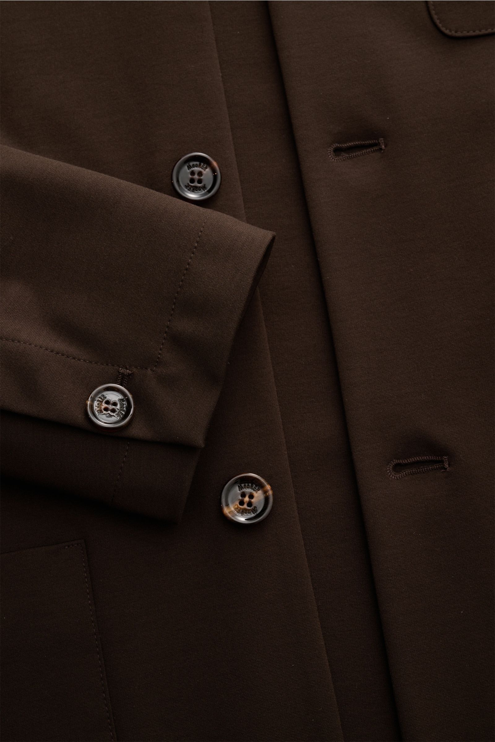 Close-up front view of Moorer Jersey-Jacke 'Keaton' dunkelbraun showing texture, buttons, cuff, and clean stitching details.

Description: So fühlt sich Luxus an: Die leichte Jacke 'Keaton' von MOORER im Overshirt-Stil kombiniert edlen Materialmix mit 