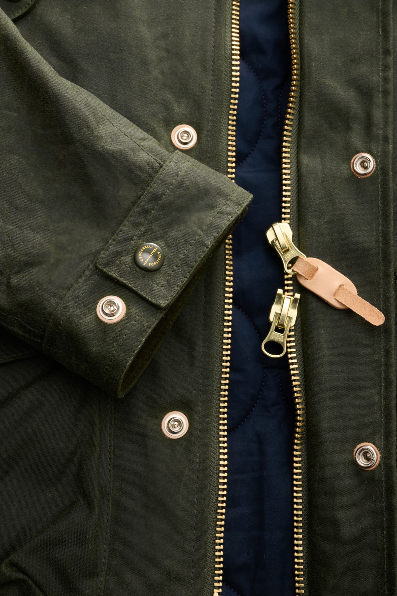 Alt-Tag (124 Zeichen): Nahaufnahme der Manifattura Ceccarelli Wachsjacke 'New Fisherman' oliv mit gewachster Baumwolle, Reißverschluss und Druckknöpfen.
