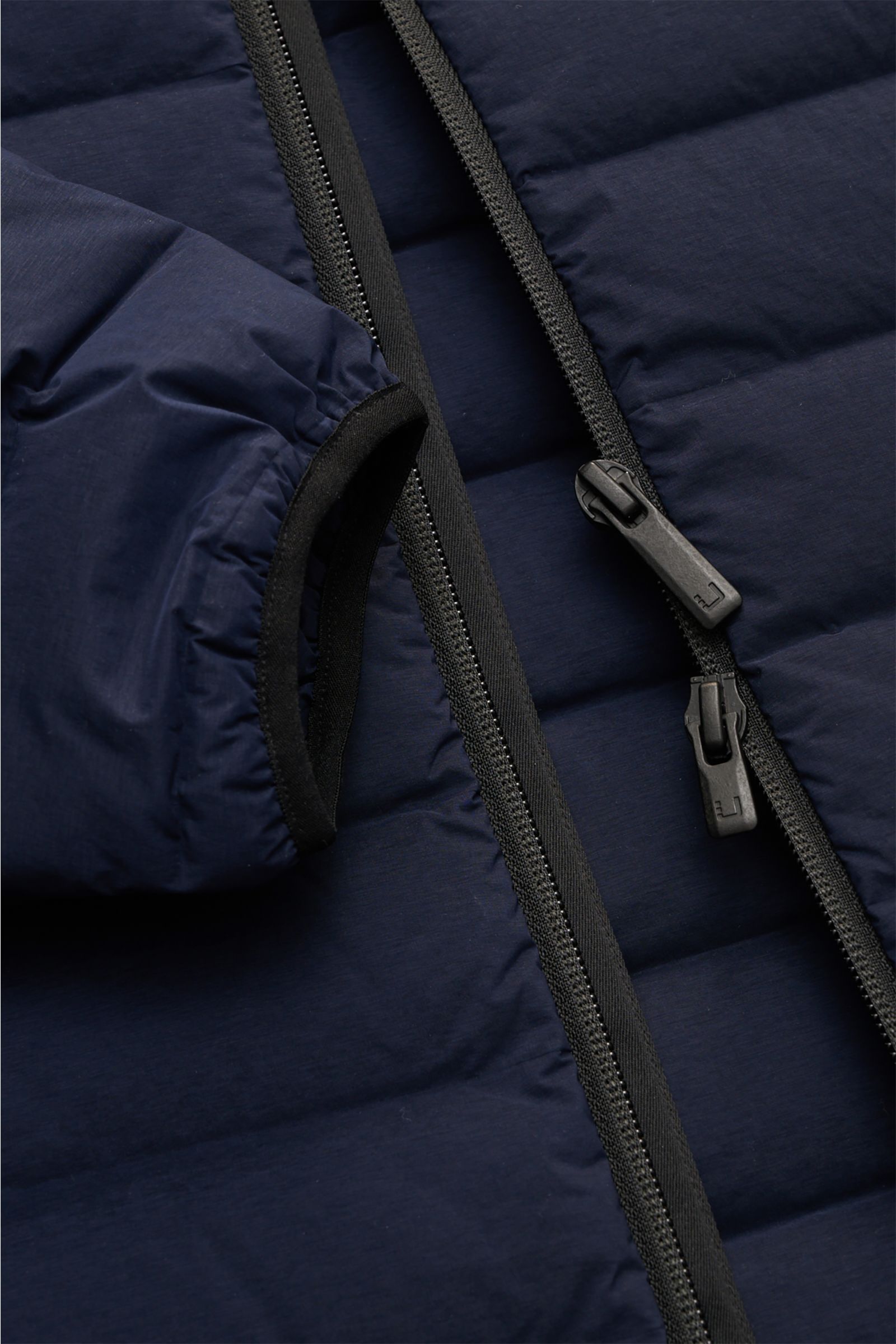 Nahaufnahme der UBR Daunenjacke 'Supersonic' navy von oben mit sichtbar elastischem Ärmel, Zwei-Wege-Reißverschluss und feiner Microfaser.