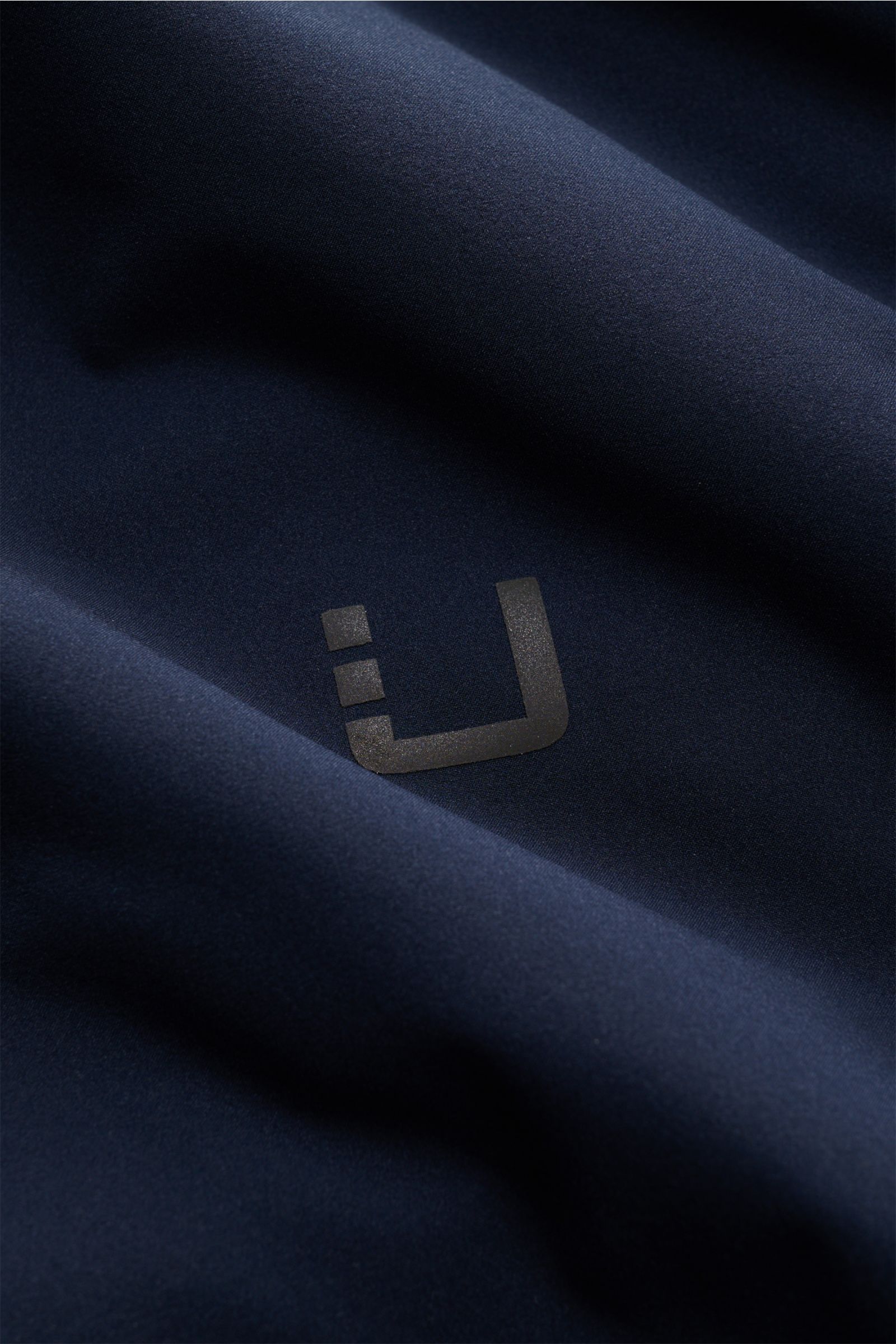 UBR Jacke 'Viper' navy Detailaufnahme des hochwertigen, elastischen, wasserabweisenden Microfaserstoffs mit reflektierendem Logo-Print.