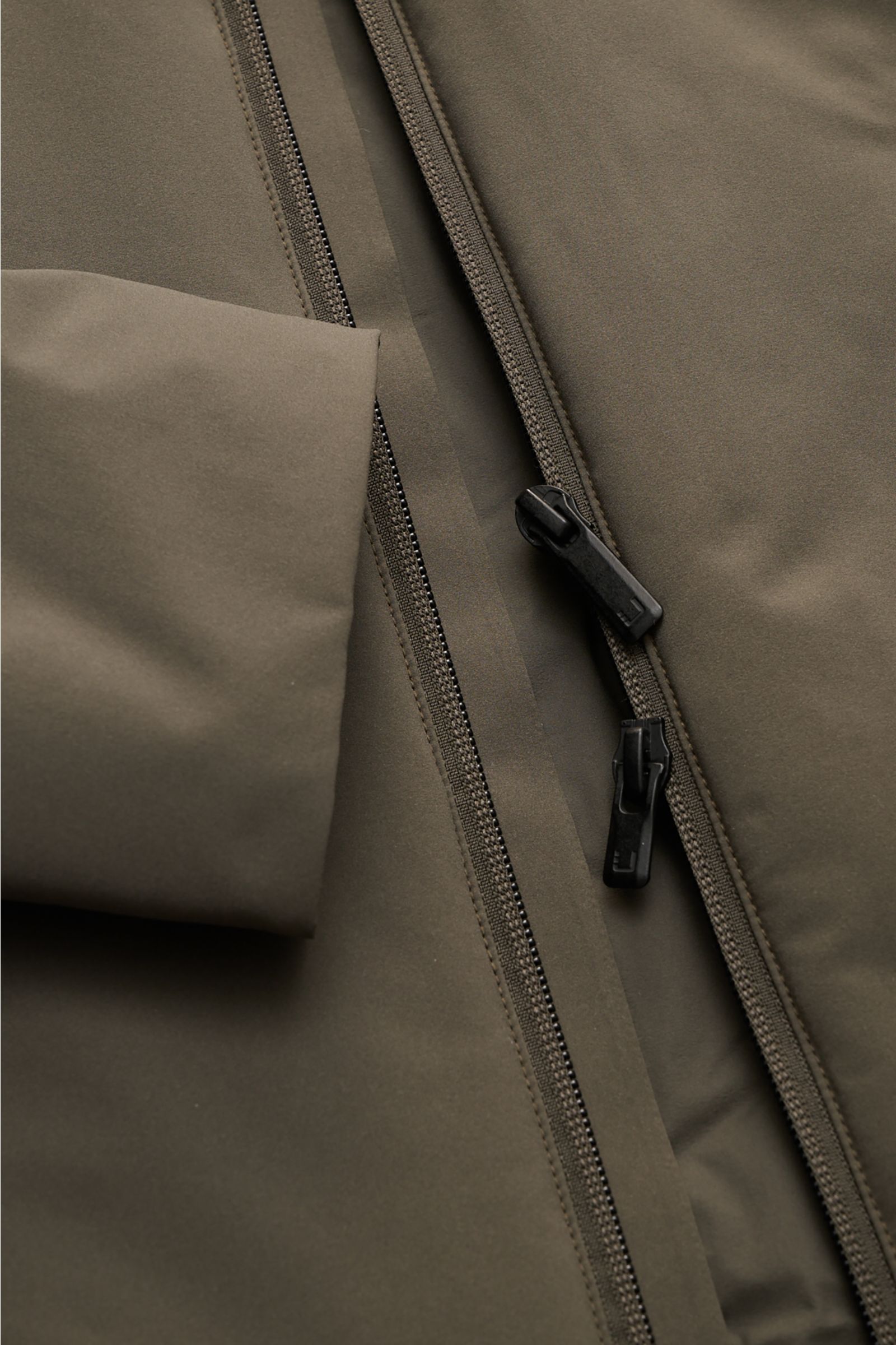 Close-up front view of the UBR Jacket 'Viper' grey-green showing its two-way zip and stretchy microfibre fabric, highlighting water repellent, slim fit, elastic cuffs, and reflective details. UBR are the experts when it comes to the finest materials and i