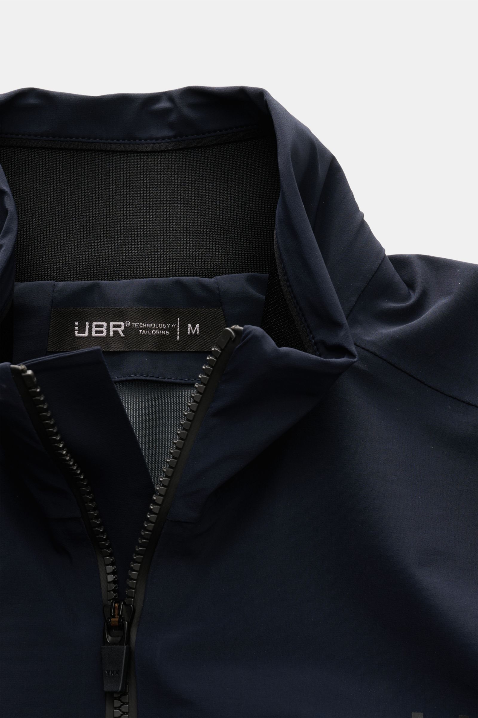 Close-up front view of the UBR Blouson 'Delta' navy, showcasing the stand collar with rib-knit lining and black zipper. 