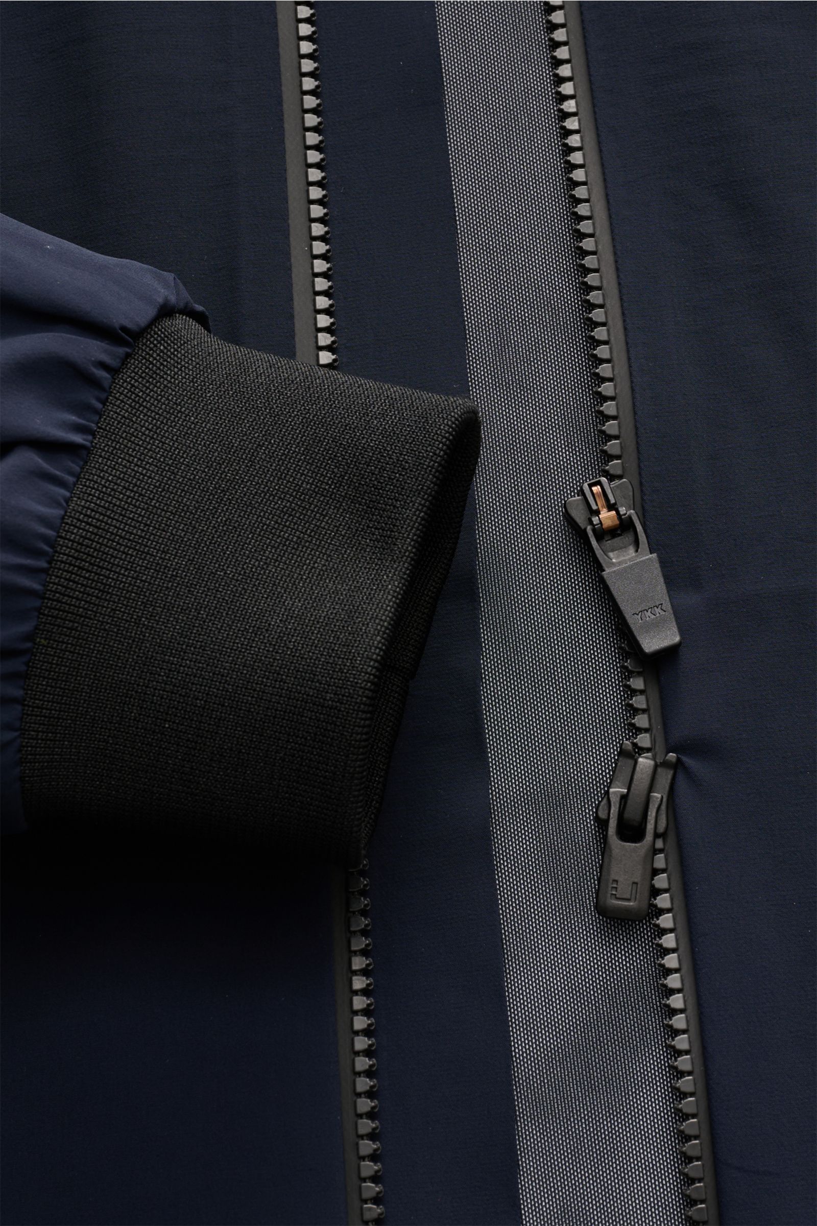 Close-up front view of the navy UBR Blouson 'Delta' showing the black ribbed cuff and two-way zipper with reflective strip, 