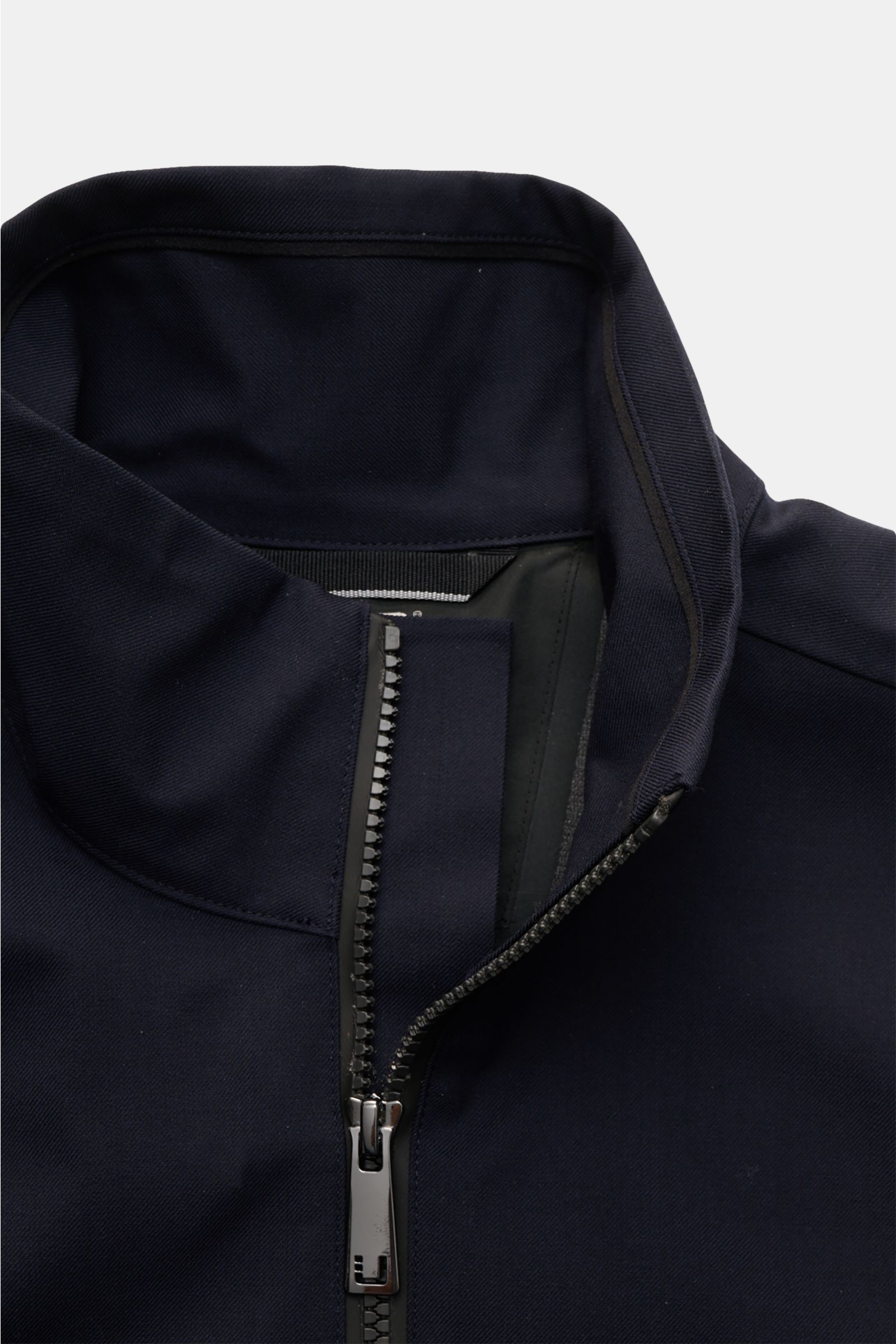 Close-up front view of the UBR Blouson 'Bullet Savile' navy showing the standing collar and partially zipped high-closing two-way zipper, made from fine wool and microfibre twill. Minimalist and functional: With its ultra lightweight design and the fine w