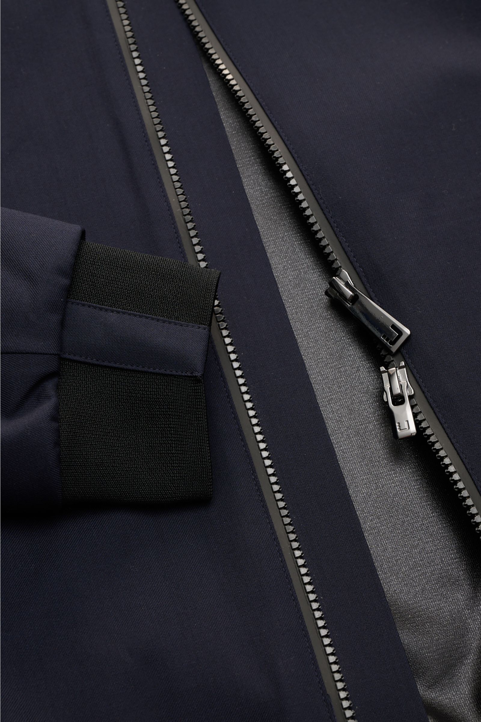 Close-up front view of the UBR Blouson 'Bullet Savile' navy showing its dual silver zipper and black flexible knit cuff. Minimalist and functional: With its ultra lightweight design and the fine wool fabric, this 'Bullet Savile' blouson from UBR is a styl