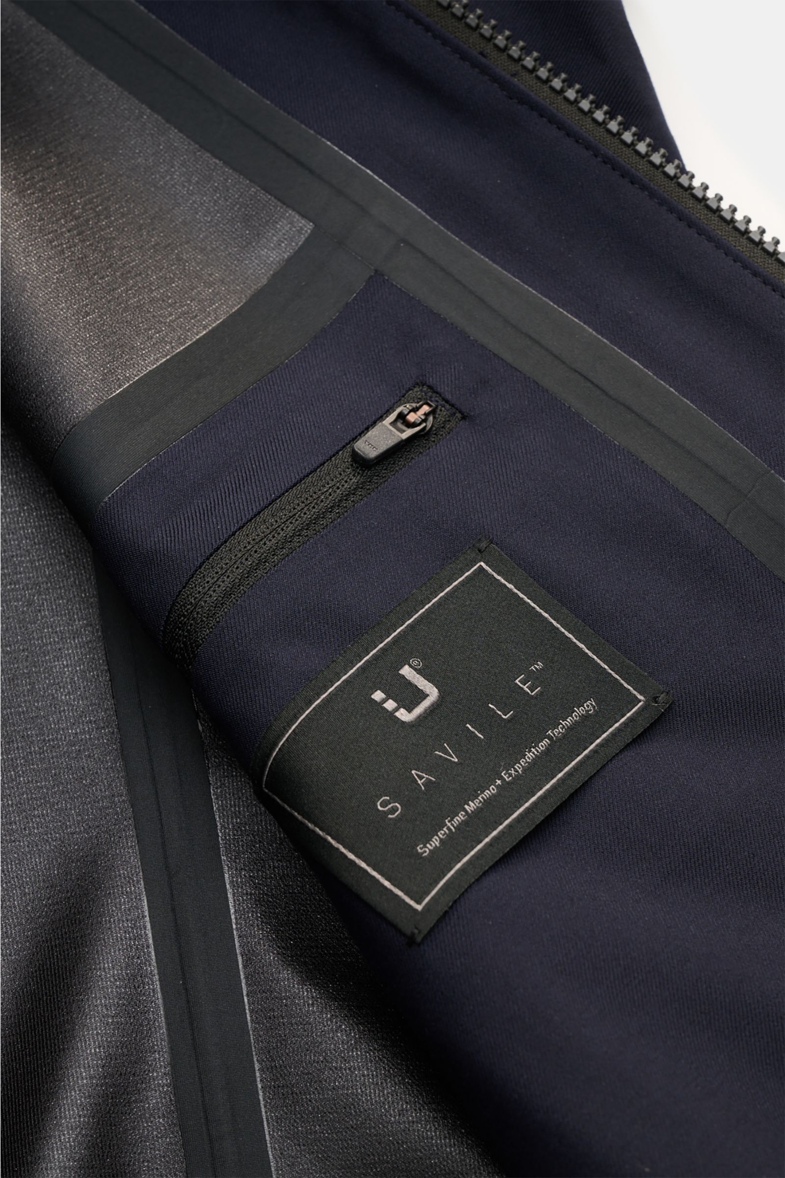Close-up interior view of the UBR Blouson 'Bullet Savile' navy showing fine wool fabric, sealed seams, inside pocket with zip, and label. Minimalist and functional: With its ultra lightweight design and the fine wool fabric, this 'Bullet Savile' blouson f