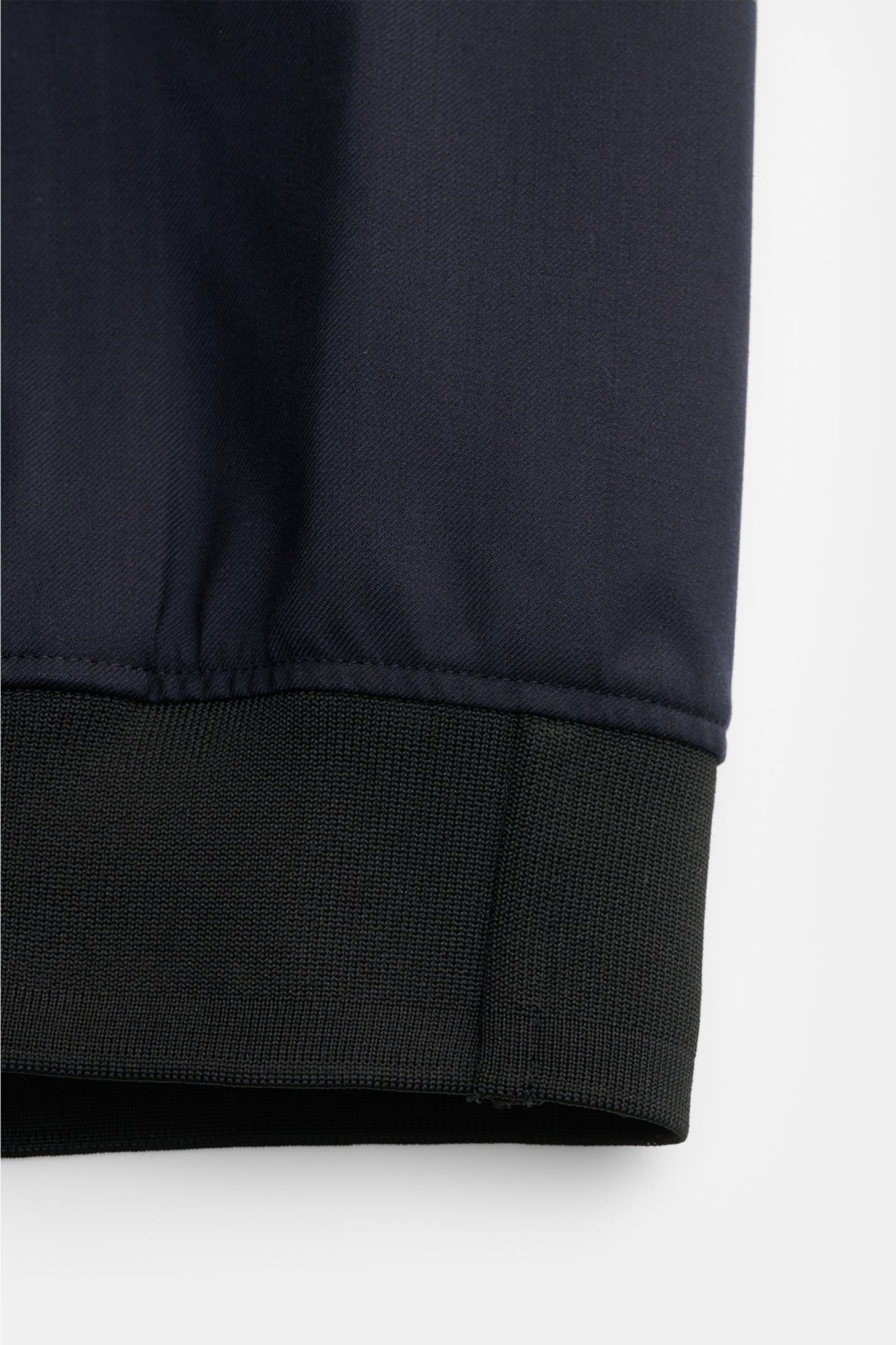 Close-up view of the navy blue UBR Blouson 'Bullet Savile' showing the fine wool fabric and black flexible knit band cuff. Minimalist and functional: With its ultra lightweight design and the fine wool fabric, this 'Bullet Savile' blouson from UBR is a st
