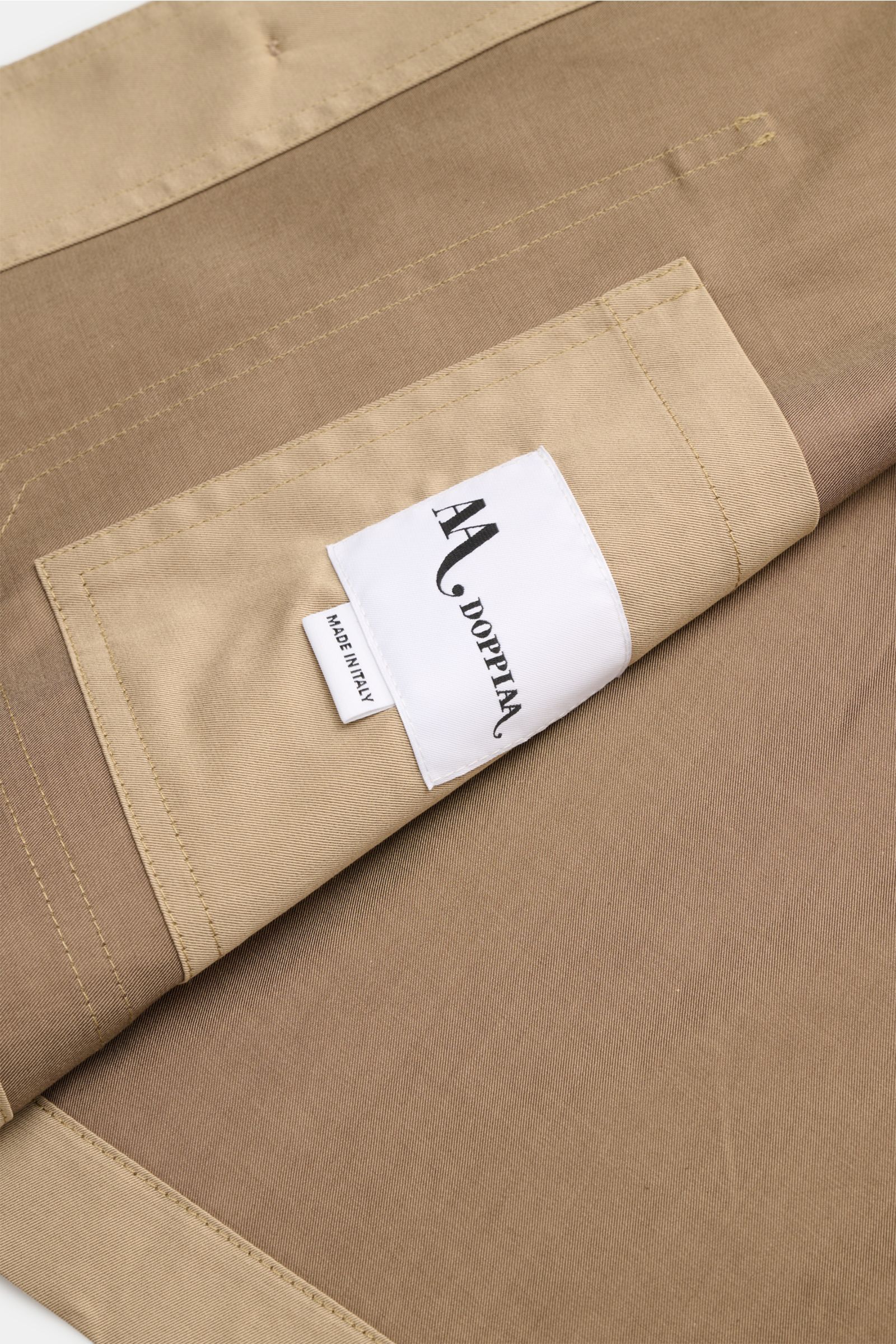 Close-up front view of the beige Doppiaa Overshirt 'Aasti' showing fine twill fabric, neat stitching, and a white label 'Made in Italy'. Versatile style for spring and summer: The subtle workwear charm of the lightweight cotton 'Aasti' overshirt from DOPP