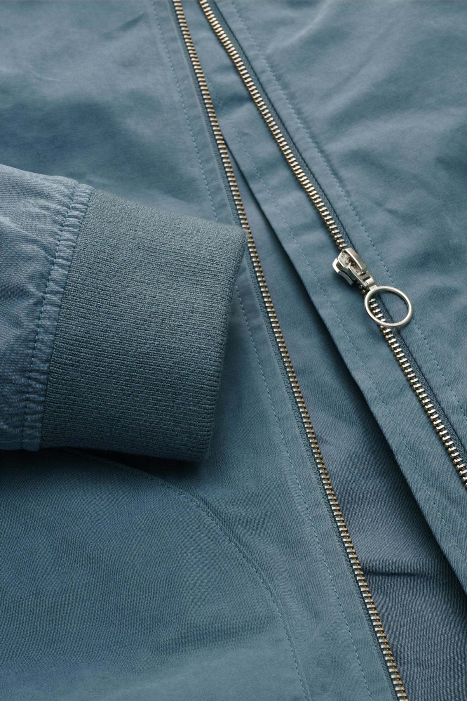 Nahaufnahme des rauchblauen 04651/ A trip in a bag Blouson 'Peached Cotton' mit Reißverschluss, elastischem Ärmelbündchen und weichem Material.