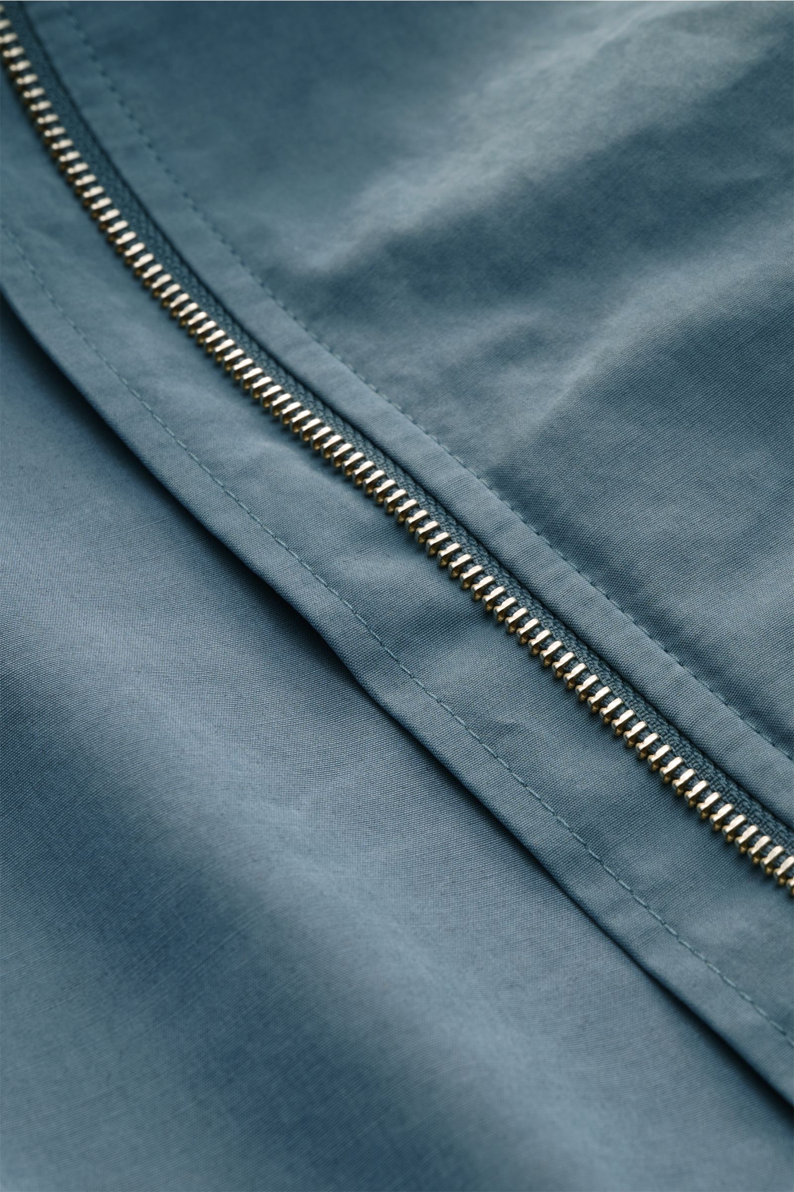 Nahaufnahme des robusten Reißverschlusses am rauchblauen 04651/ A trip in a bag Blouson 'Peached Cotton' aus Baumwoll-Microfaser-Mix mit softem Griff.