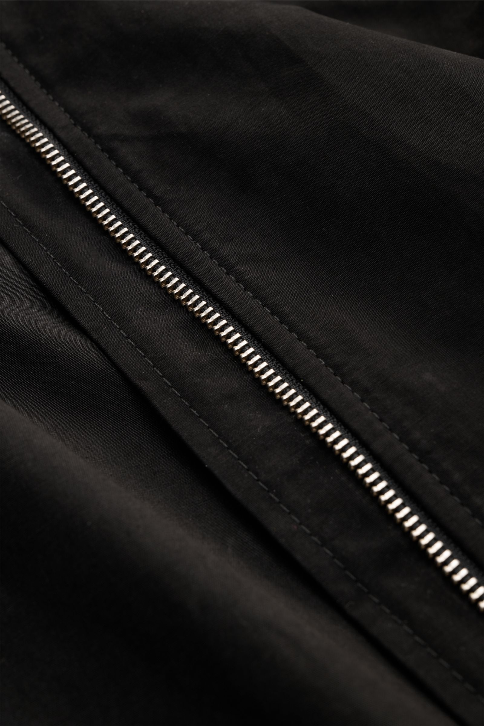 Nahaufnahme des robusten Reißverschlusses eines schwarzen 04651/ A trip in a bag Blouson 'Peached Cotton' mit softem Baumwoll-Mix und Retro-Design.