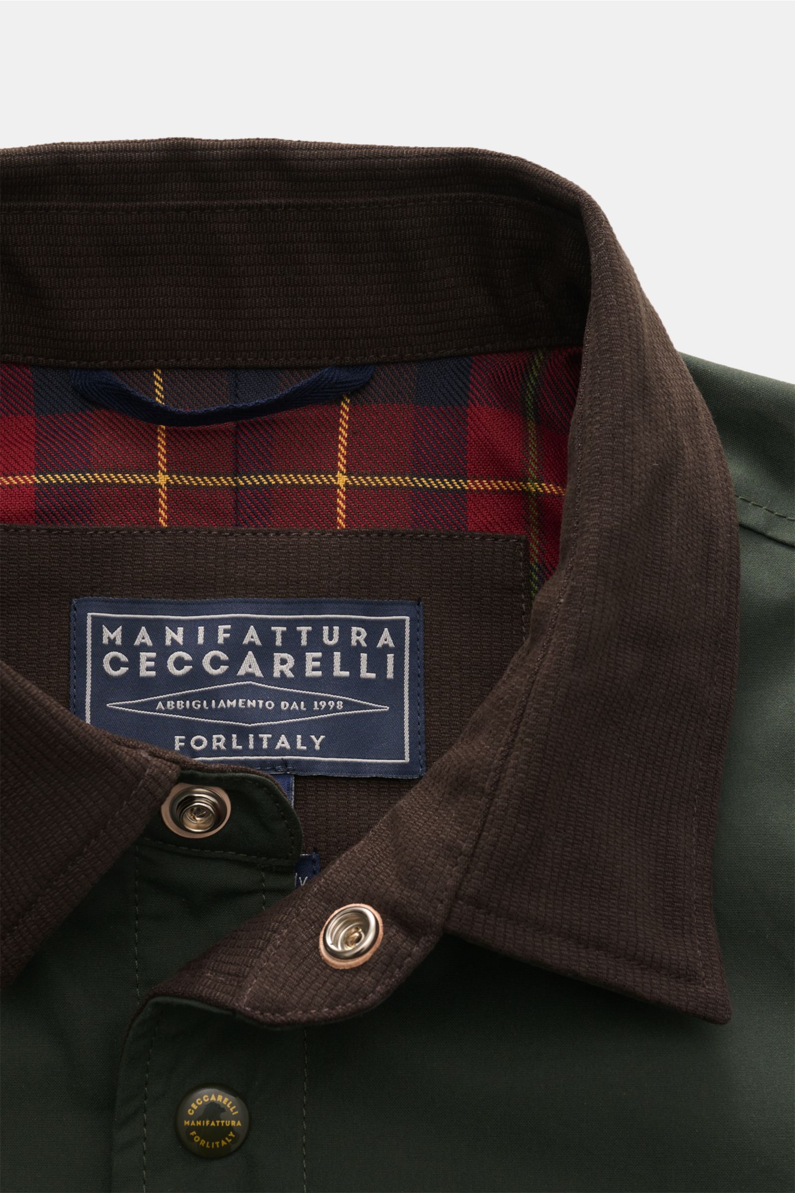 Nahaufnahme aus schräger Perspektive der dunkelgrünen Manifattura Ceccarelli Wachsjacke 'Heavy Shirt' mit Cordkragen, Tartanfutter, Druckknöpfen und gewachster, wasserabweisender, atmungsaktiver Baumwolle.