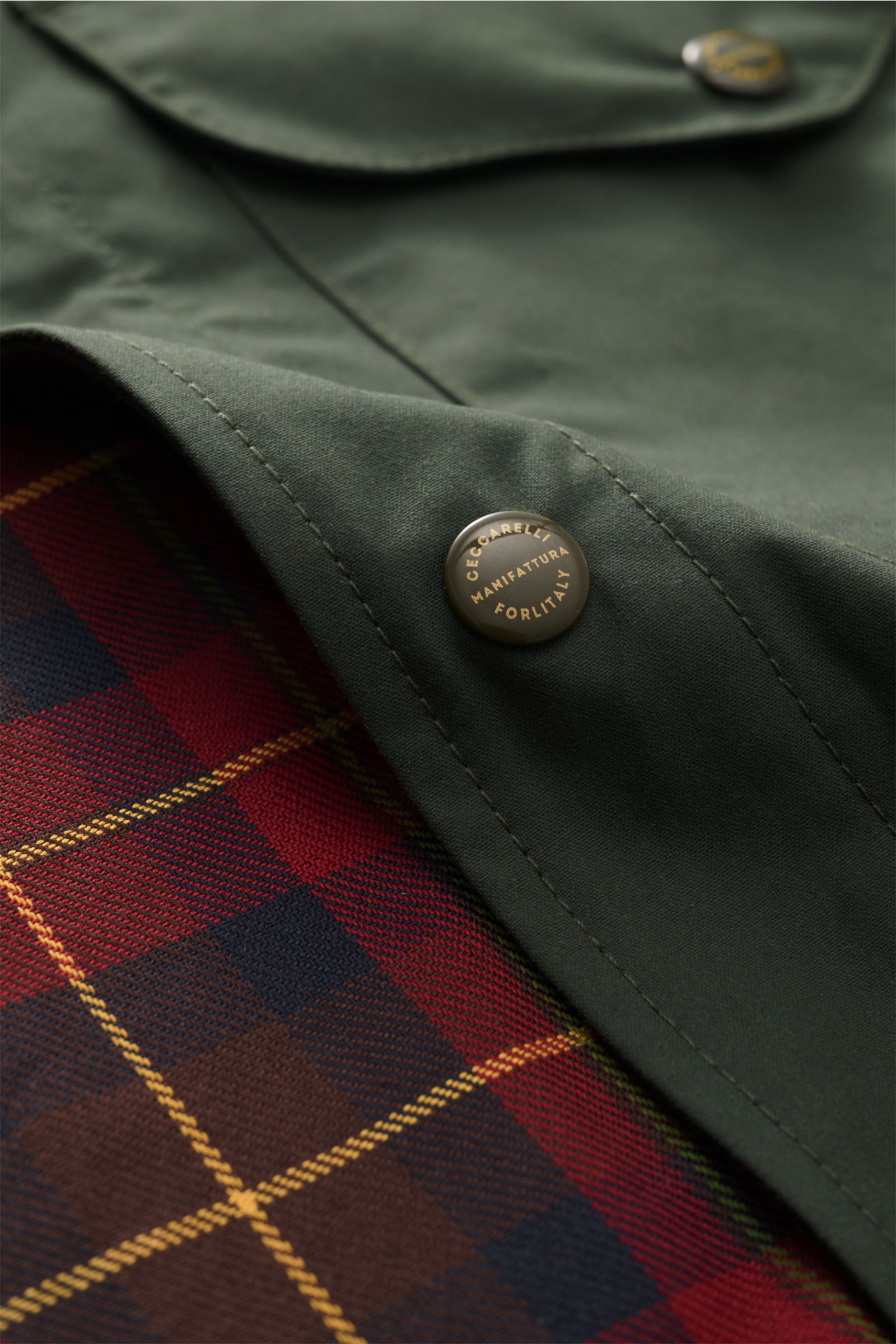 Nahaufnahme der dunkelgrünen Manifattura Ceccarelli Wachsjacke 'Heavy Shirt' mit gewachster Baumwolle, Tartan-Futter und Druckknopf.