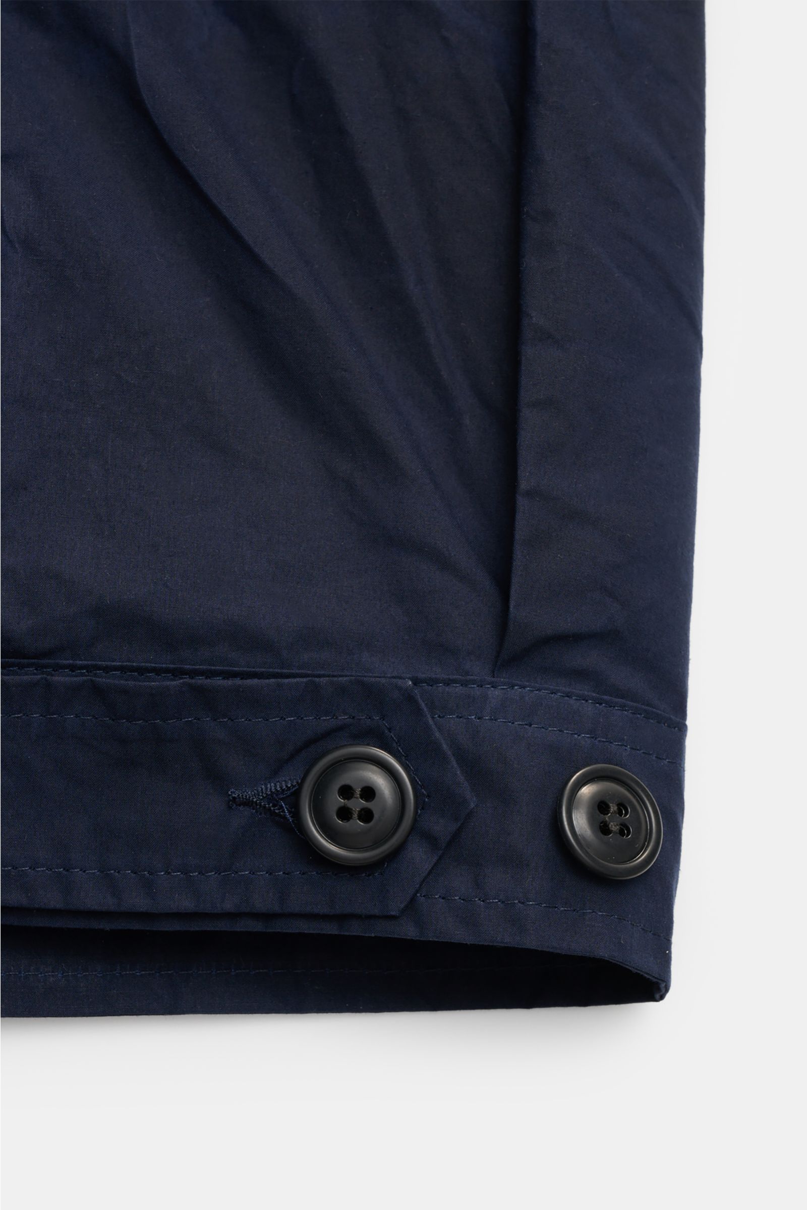 Close-up of the cuff of the Manifattura Ceccarelli Waxed jacket 'Blazer Coat' navy, showing two black buttons on waxed cotton fabric from a top-down perspective. Authentic outerwear with vintage character: This Italian-made wax jacket by MANIFATTURA CECCA