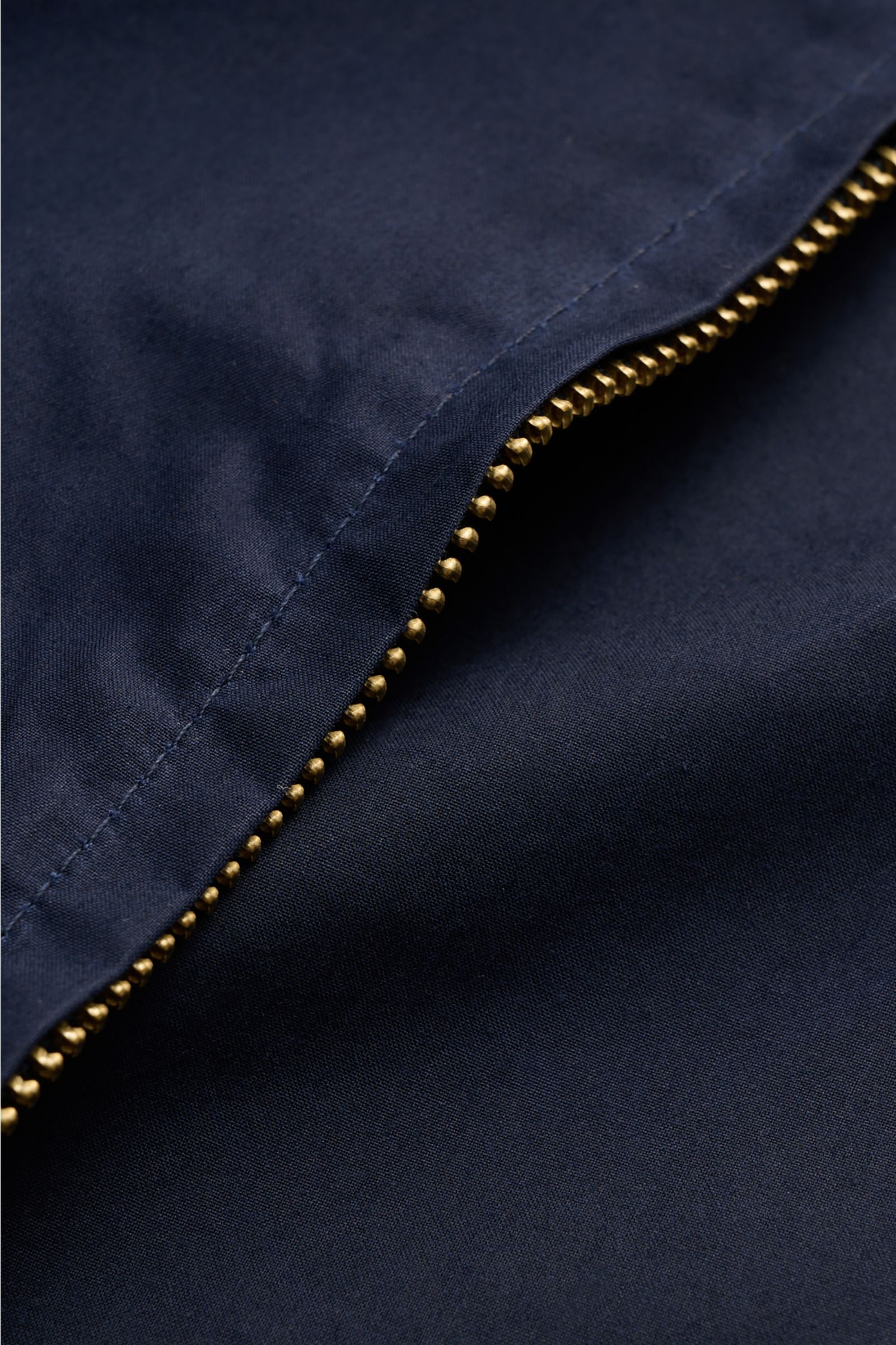 Close-up view of the Manifattura Ceccarelli Waxed jacket 'Blazer Coat' navy, showing the navy waxed cotton fabric and robust brass two-way zipper. Authentic outerwear with vintage character: This Italian-made wax jacket by MANIFATTURA CECCARELLI features 
