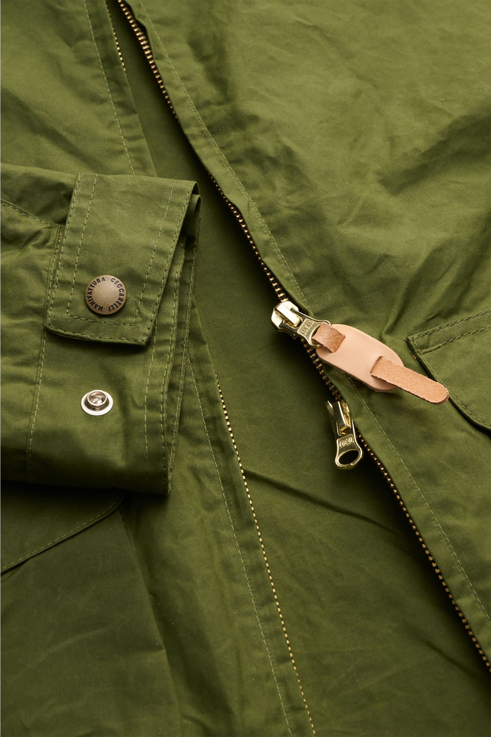 Nahaufnahme der grünen Manifattura Ceccarelli Wachsjacke 'Hooded Blazer' aus paraffinierter Baumwolle mit Zwei-Wege-Reißverschluss, Knopfärmel und Fronttaschen.
