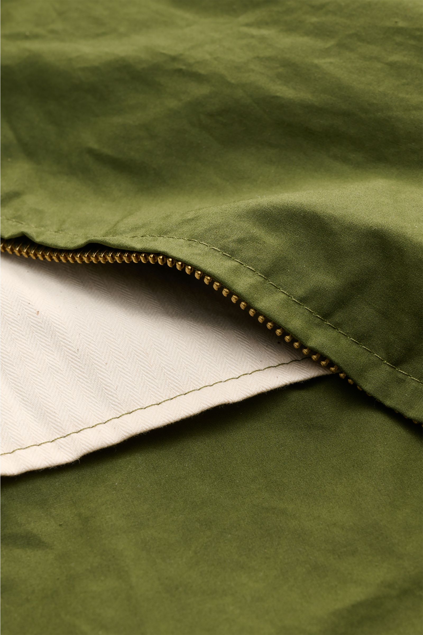 Nahaufnahme der grünen Manifattura Ceccarelli Wachsjacke 'Hooded Blazer' mit paraffiniertem Baumwollgewebe, Reißverschluss und Innenfutter.