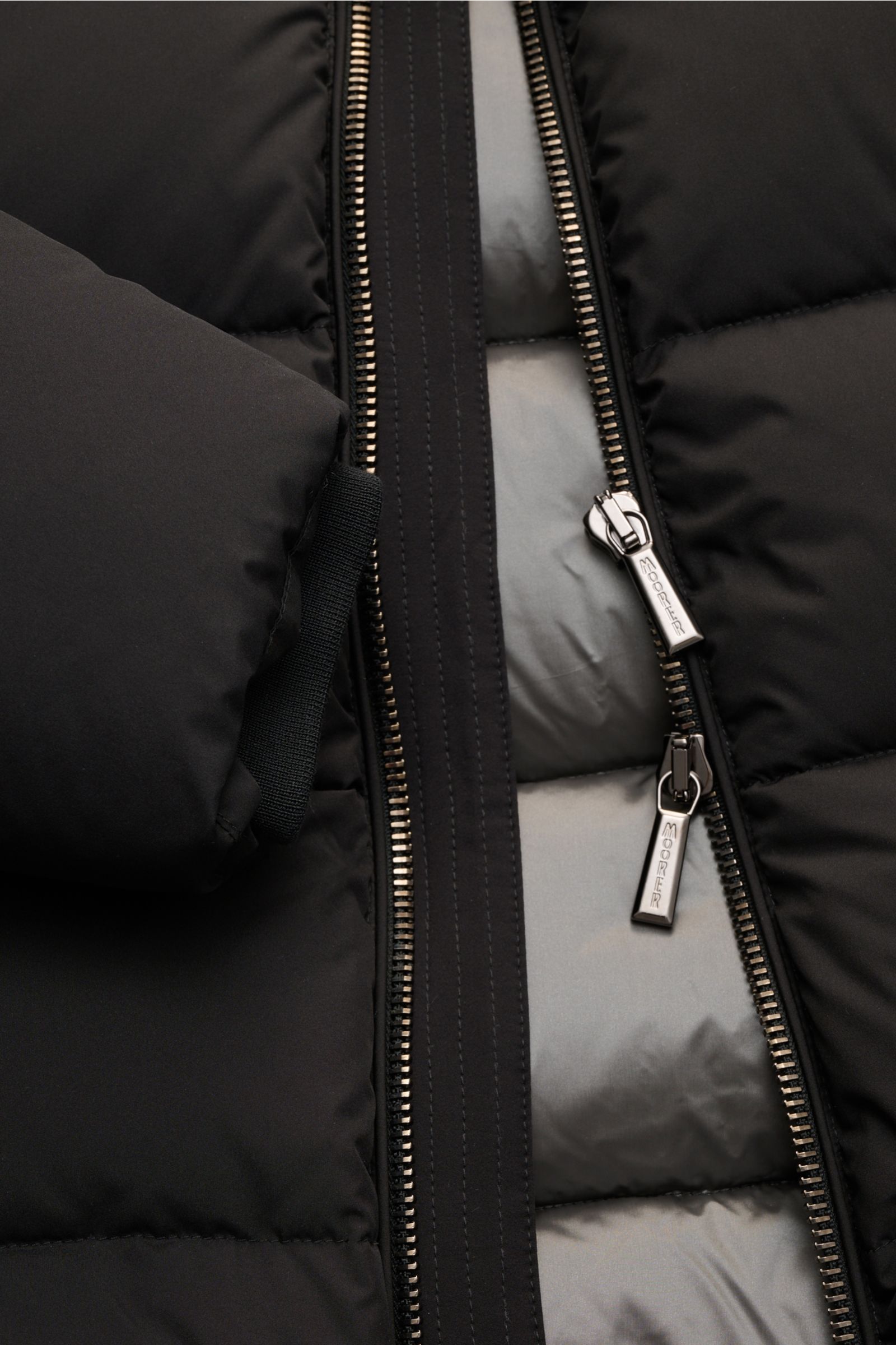 Nahaufnahme der Moorer Daunenjacke 'Brett' schwarz von vorne mit offenem Zwei-Wege-Reißverschluss, abnehmbarer Kapuze, Slim Fit und wärmender Daunenfüllung.