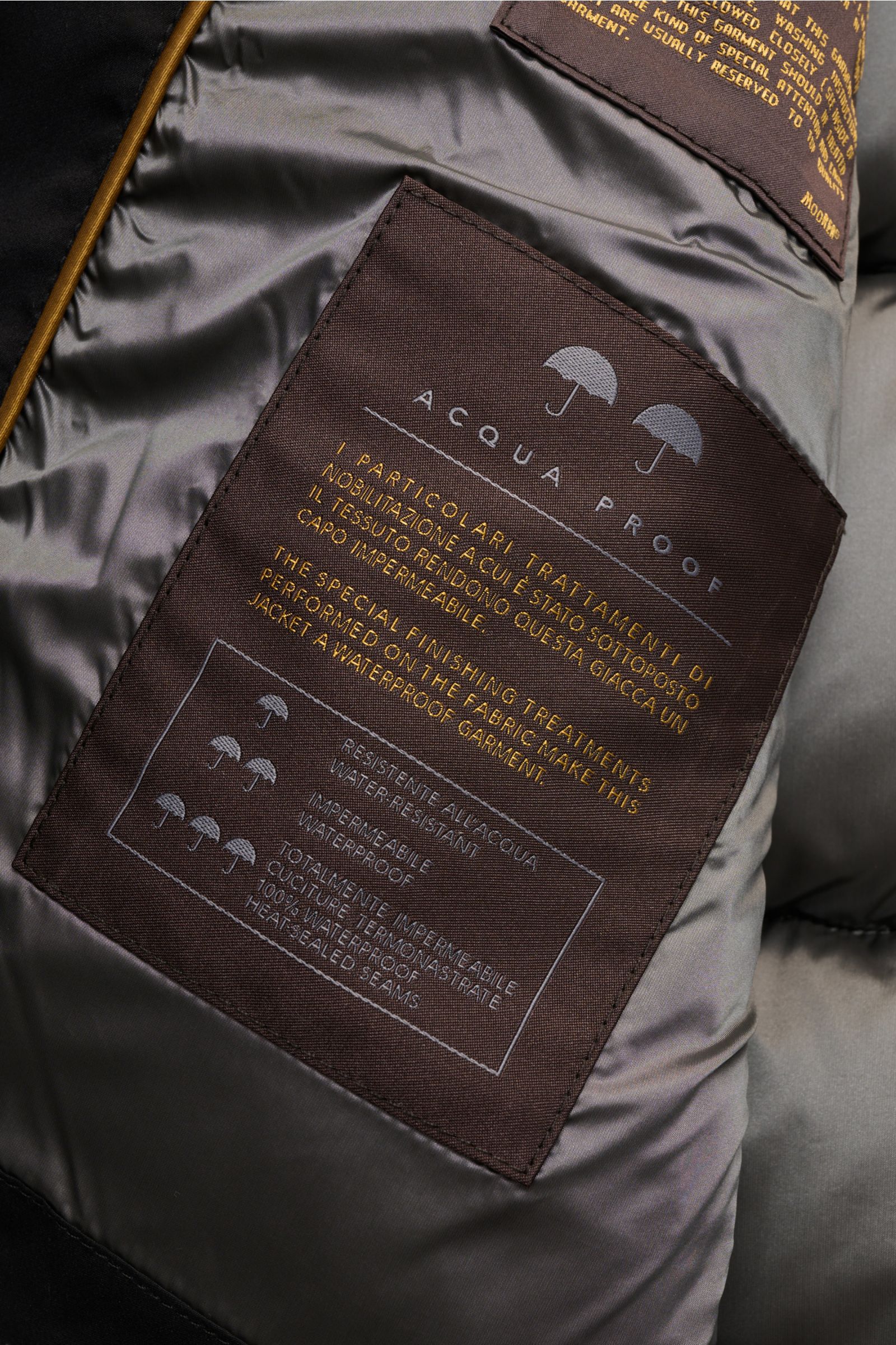 Nahaufnahme des Innenfutters der Moorer Daunenjacke 'Brett' schwarz, Detailansicht mit wasserabweisendem Material und Pflegeetikett.