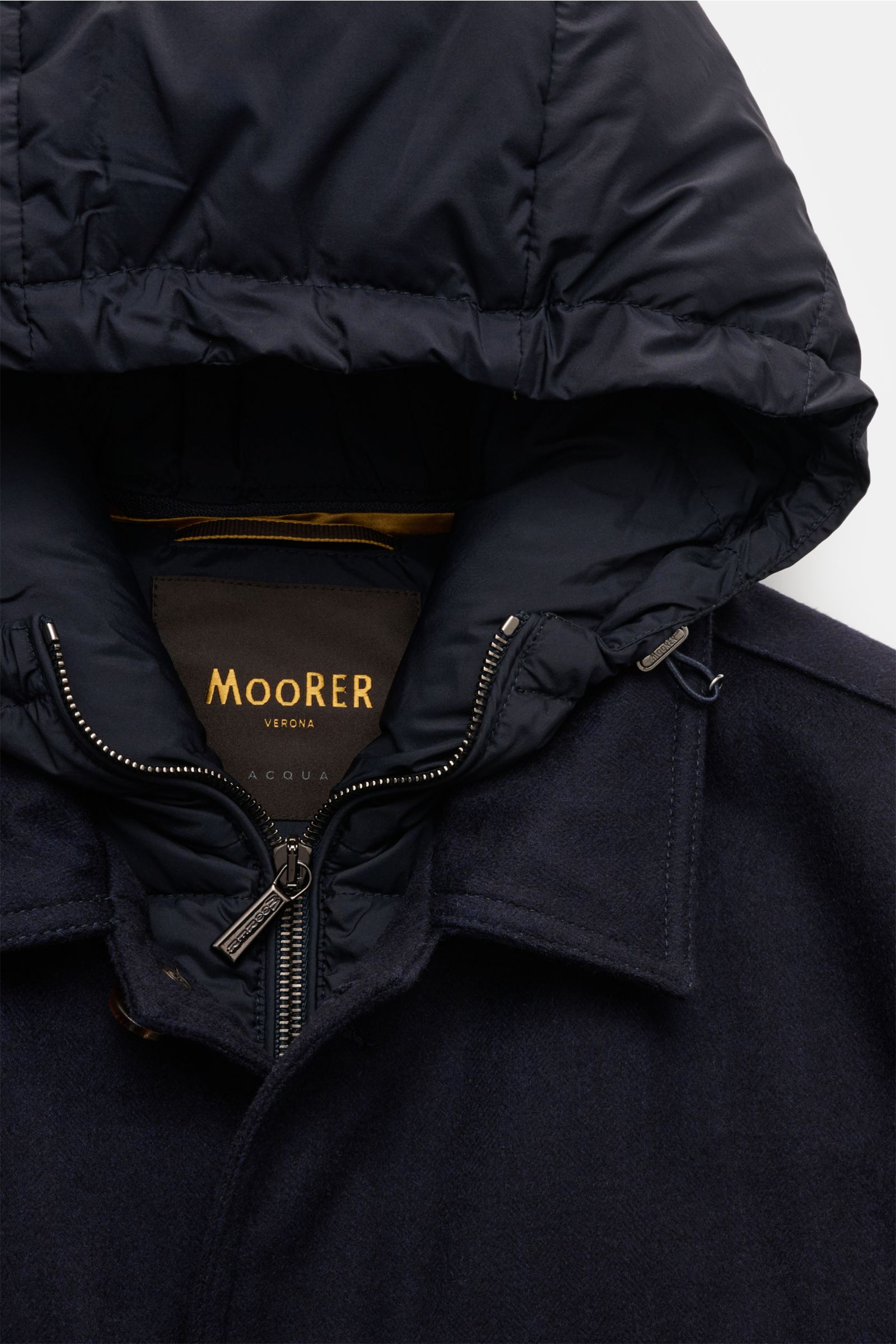 Nahaufnahme der Moorer Daunenjacke 'Monti' navy von oben, zeigt Umlegekragen, wasserabweisende Kapuze mit Reißverschluss und Woll-Cashmere-Mix.