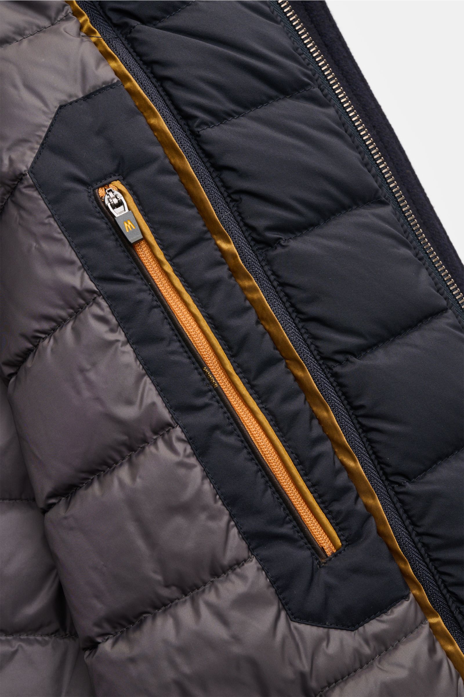 Nahaufnahme des Innenfutters der Moorer Daunenjacke 'Monti' navy mit gestepptem Futterstoff, Innentasche und Reißverschluss.