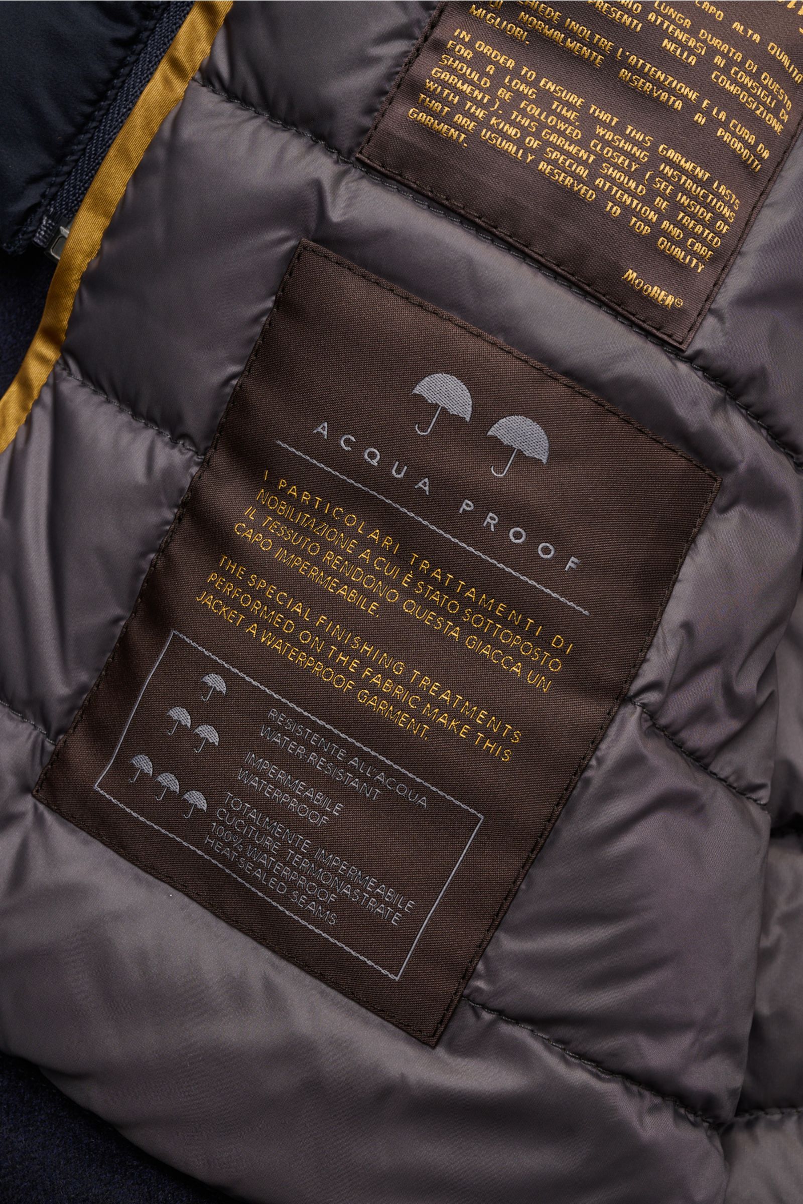 Innenansicht der Moorer Daunenjacke 'Monti' navy mit wasserabweisendem, gestepptem Futter und Pflegeetiketten, Detailfoto.