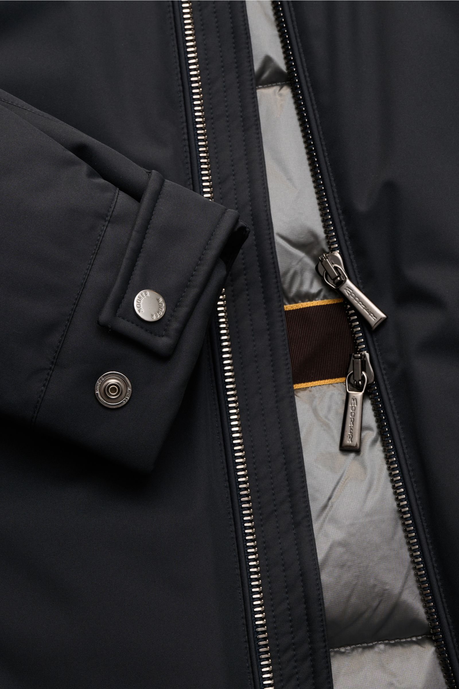 Nahaufnahme der geöffneten Moorer Jacke 'Pericle' navy mit sichtbarem Zwei-Wege-Reißverschluss, Knopf-Ärmelabschluss und gestepptem Futterstoff, hochwertiger Microfaser, wind- und wasserabweisend, mit wärmender Daunenfüllung, Slim Fit.