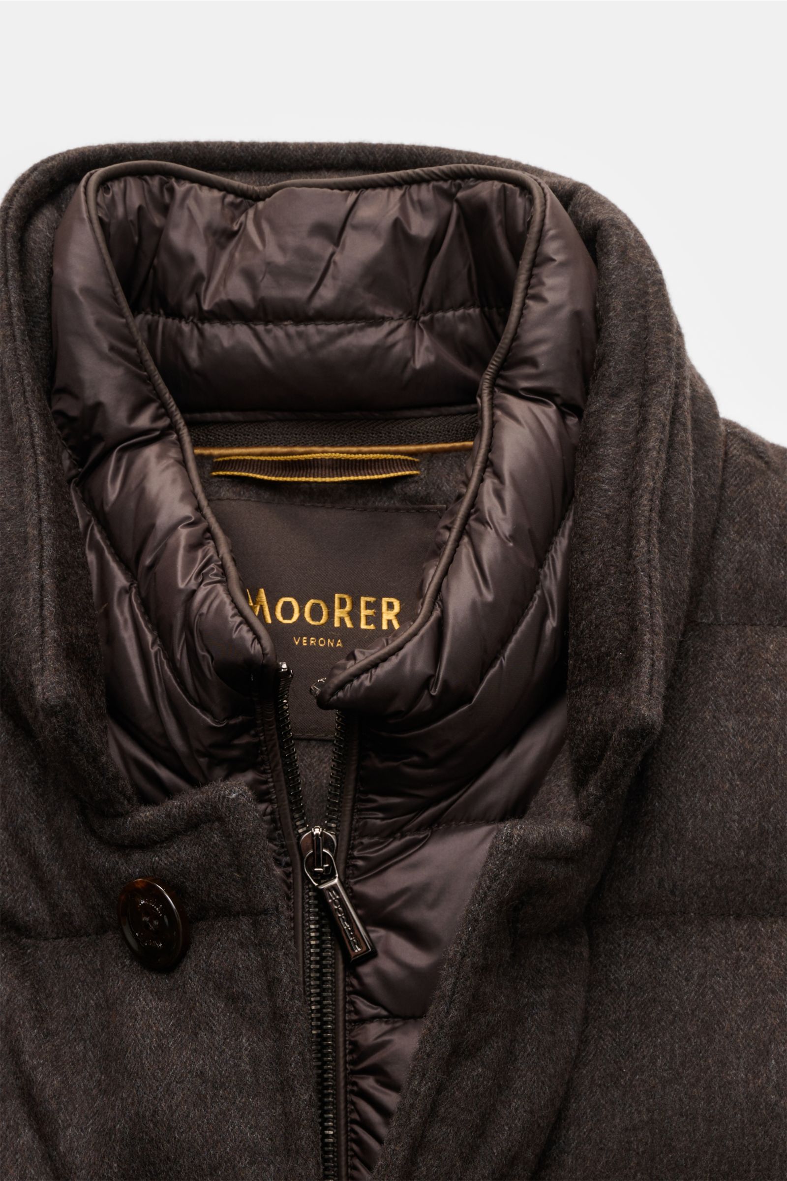 Nahaufnahme der Moorer Daunenjacke 'Costanzo' dunkelbraun, Slim Fit, aus Wolle-Cashmere-Mix mit wärmender Daunenfüllung, hoch geschlossenem Zwei-Wege-Reißverschluss und gesteppter Innenfront, fotografiert von vorne oben.