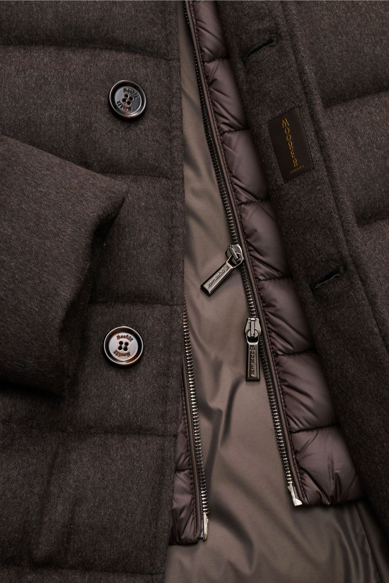 Nahaufnahme der geöffneten Moorer Daunenjacke 'Costanzo' dunkelbraun aus Wolle-Cashmere-Mix, Detailansicht mit Reißverschlüssen und Knöpfen.