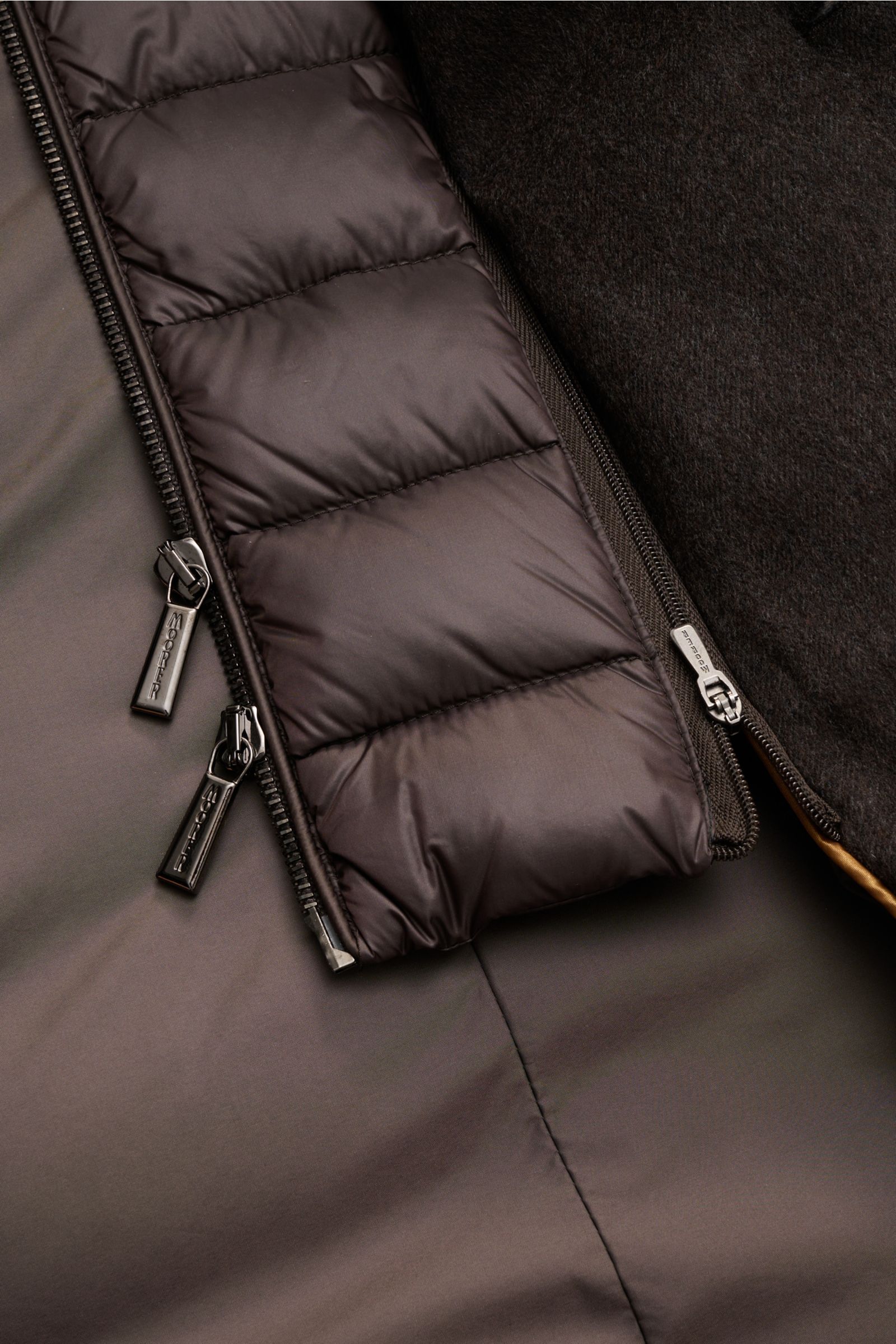 Nahaufnahme der Reißverschlüsse und Materialien der Moorer Daunenjacke 'Costanzo' dunkelbraun, gesteppter Wolle-Cashmere-Mix mit wärmender Daunenfüllung.