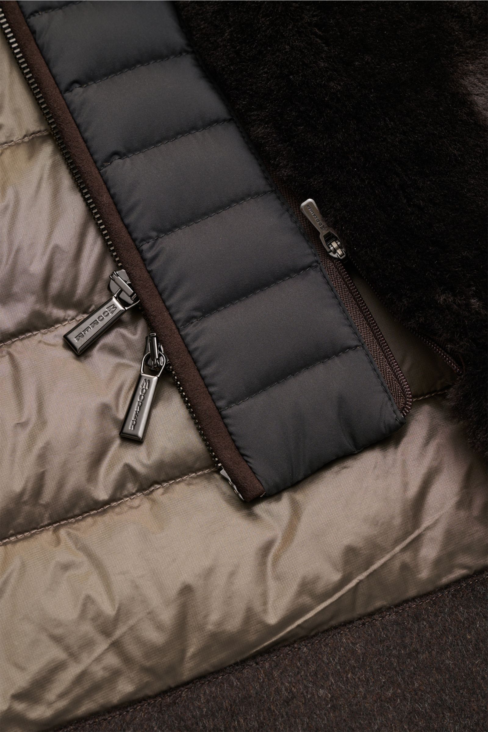 Nahaufnahme der Innenseite der Moorer Daunenjacke 'Teodor' graubraun mit herausnehmbarer Double-Front, gestepptem Futter und Reißverschlüssen.