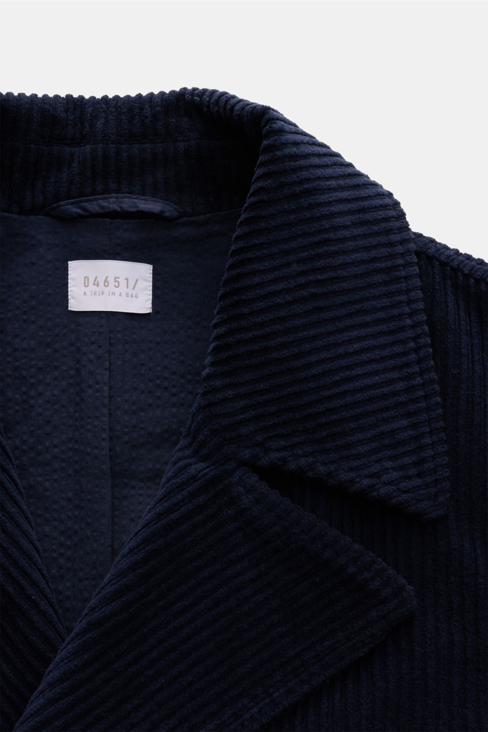 Close-up front view of the 04651/ A trip in a bag Corduroy pea coat navy showing its wide wale corduroy texture, wide lapel collar, and label inside. Make a statement this autumn with the pea coat 'Cord Peacoat' by 04651/ A TRIP IN A BAG: Its classic desi