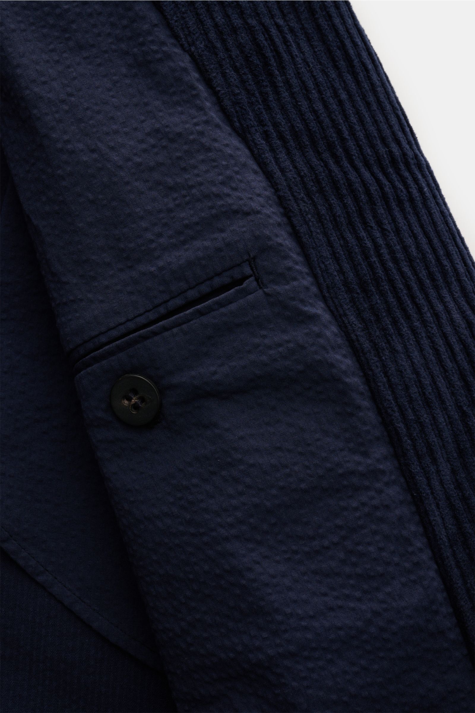Close-up front-side view of the navy 04651/ A trip in a bag Corduroy pea coat showing wide wale cotton corduroy with seersucker lining, button, and pocket details.