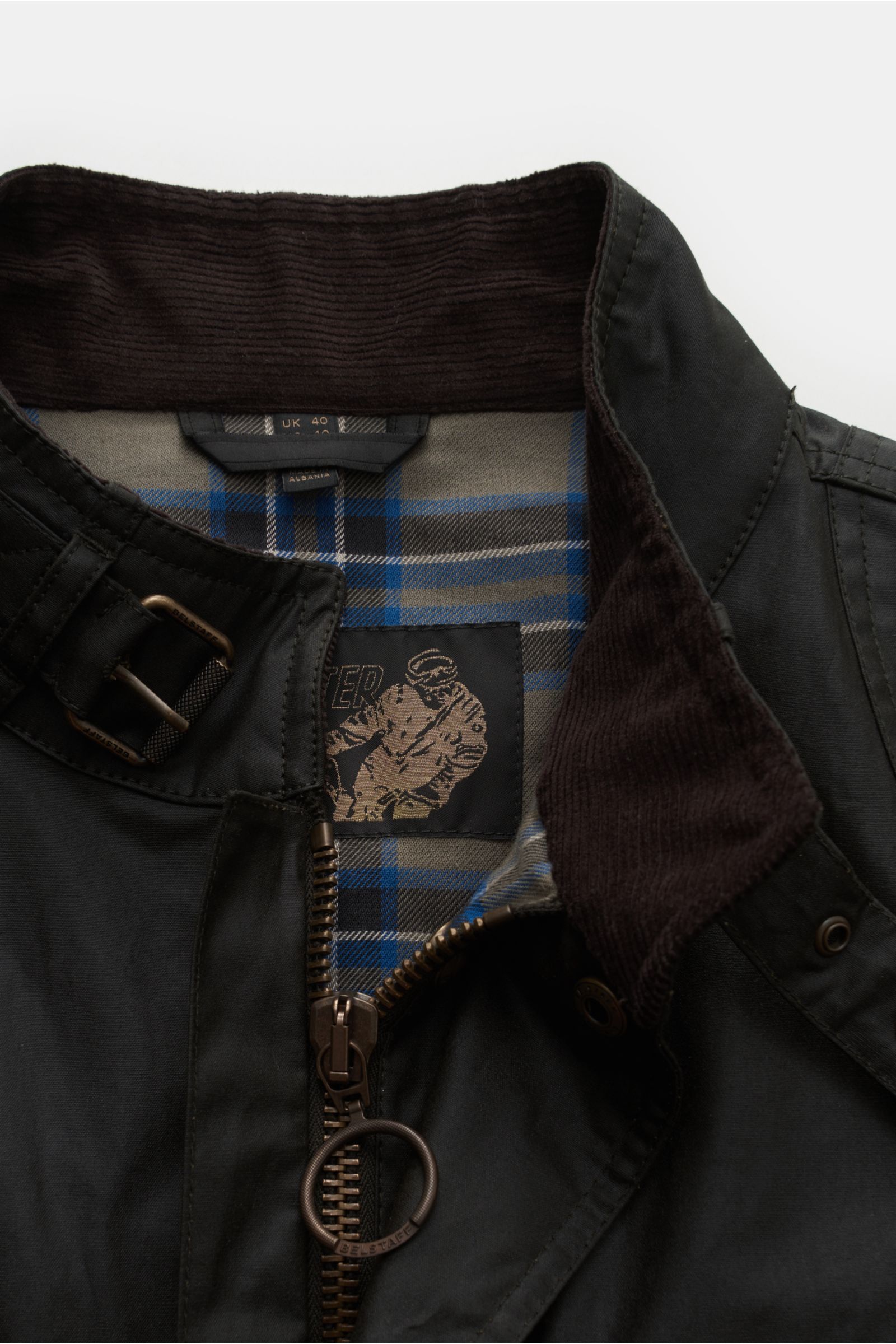 Close-up front view of Belstaff Wachsjacke 'Trialmaster' schwarz showing waxed cotton fabric, robust zipper, corduroy collar, and inner plaid lining.