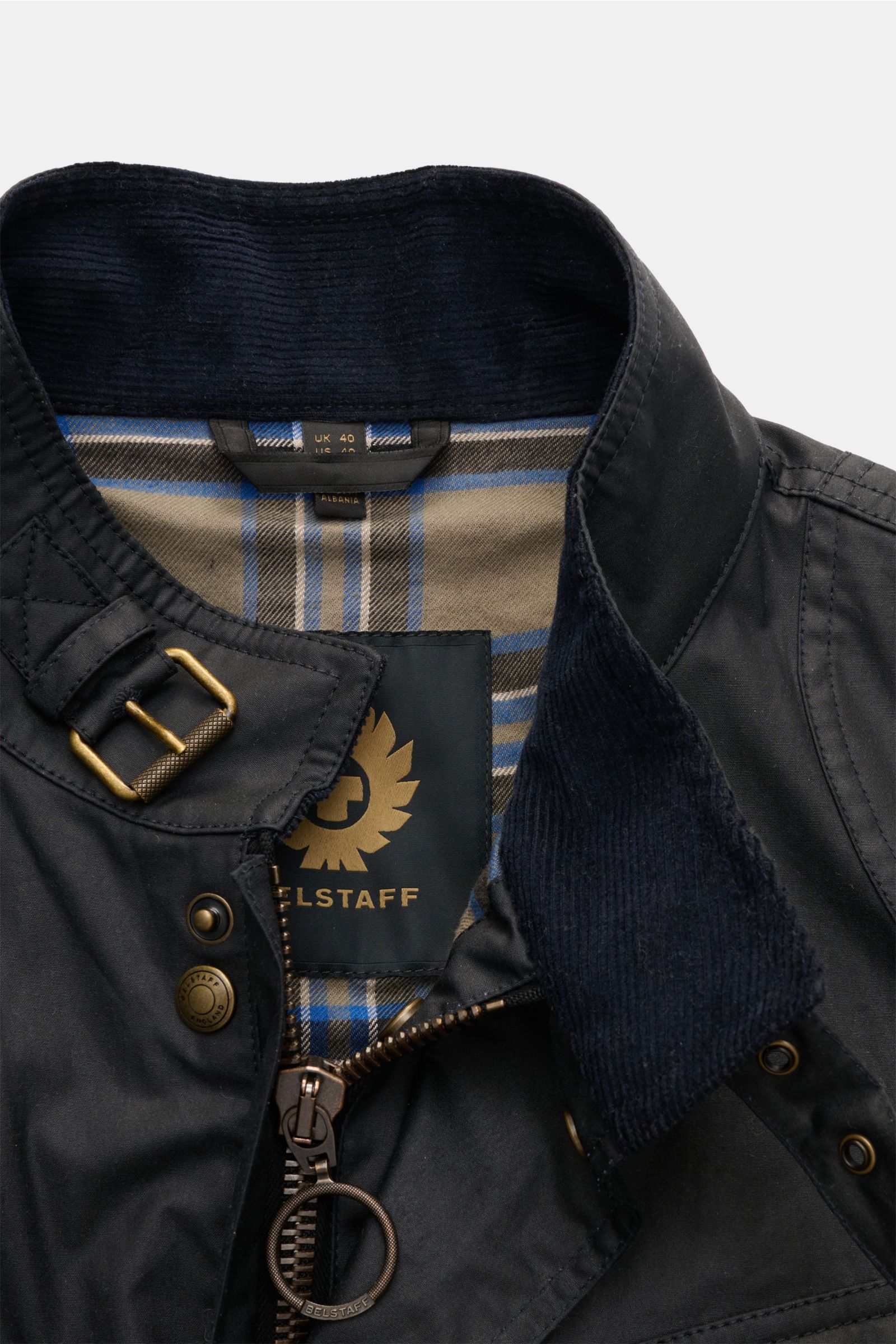 Nahaufnahme der Belstaff Wachsjacke 'Fieldmaster' dark navy von oben, zeigt Stehkragen mit Cordbesatz, Reißverschluss und karierte Baumwoll-Innenfütterung.