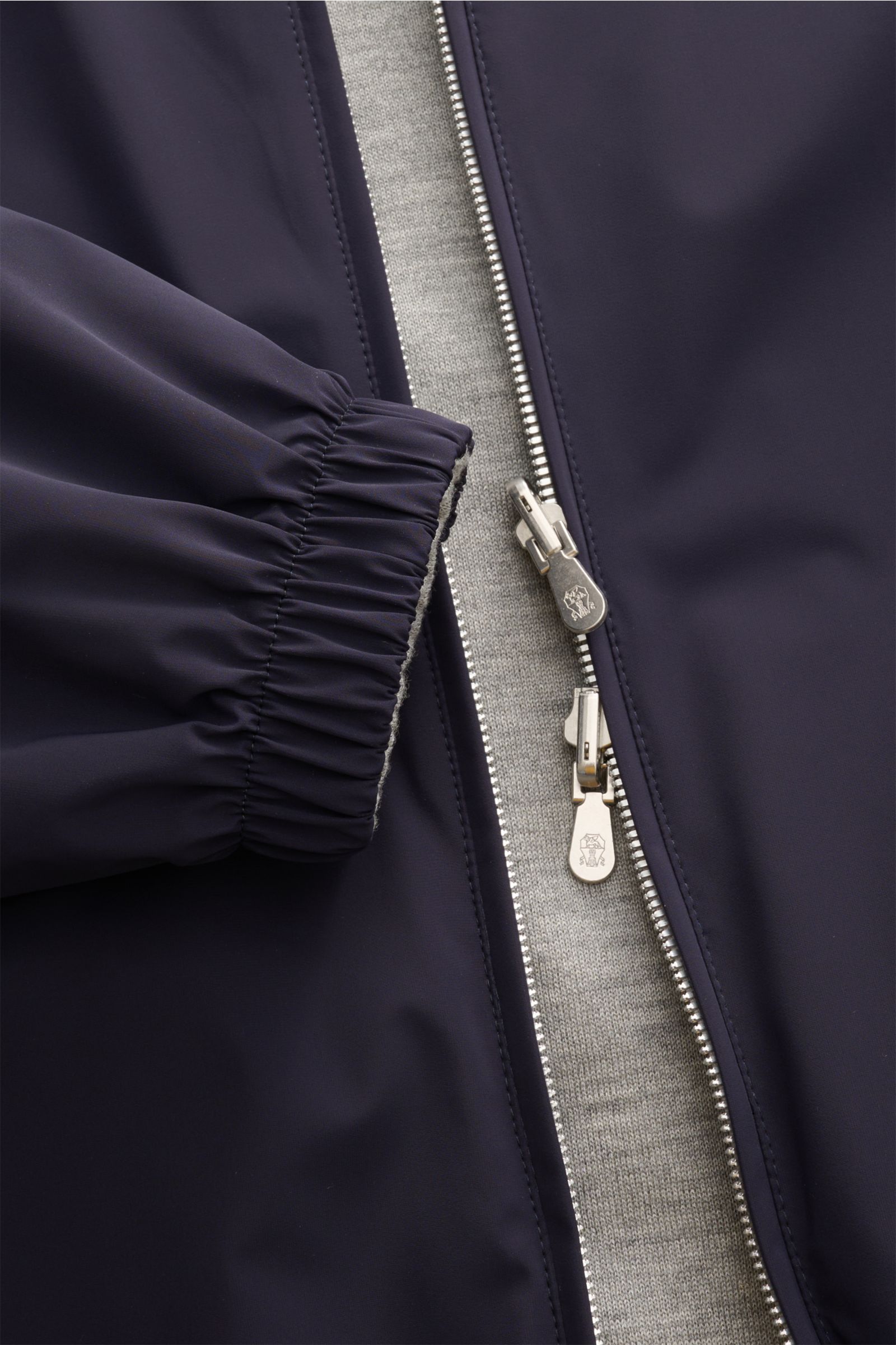 Close-up front view of Brunello Cucinelli Wendeblouson navy/grau showing navy microfiber exterior, silver zipper, and elastic cuff with grey cashmere-silk inner lining.

Additional description:
Zwei Looks, ein Anspruch: BRUNELLO CUCINELLI präsentiert m